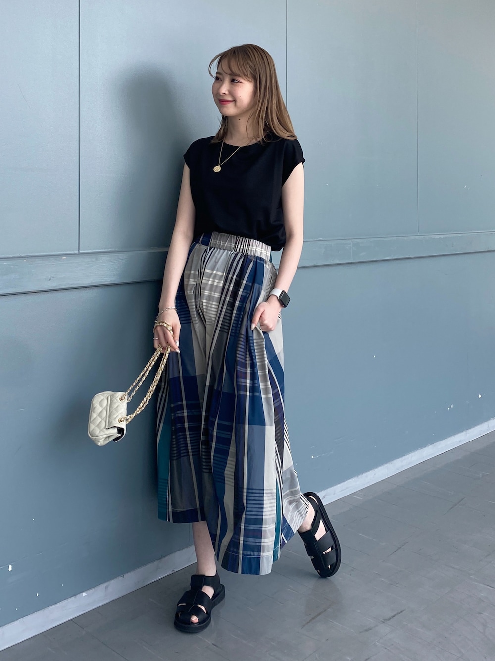 ブラック系のTシャツ/カットソー、グリーン系のスカート、ブラック系のサンダルを着用したレディースの春コーディネートの1枚目の写真