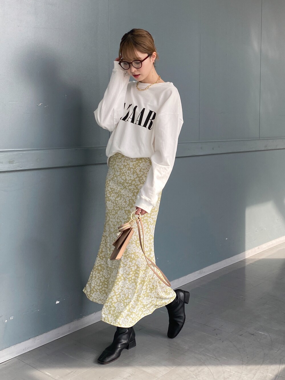 ホワイト系のTシャツ/カットソー、イエロー系のスカート、ベージュ系のショルダーバッグを着用したレディースの冬コーディネートの1枚目の写真