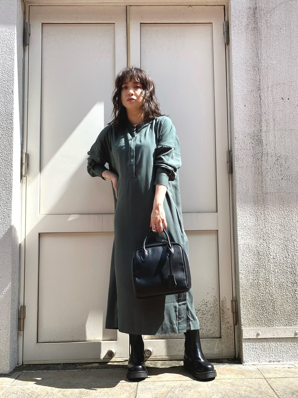 グリーン系のワンピース、ブラック系のショルダーバッグ、ブラック系のブーツを着用したレディースの秋コーディネートの1枚目の写真