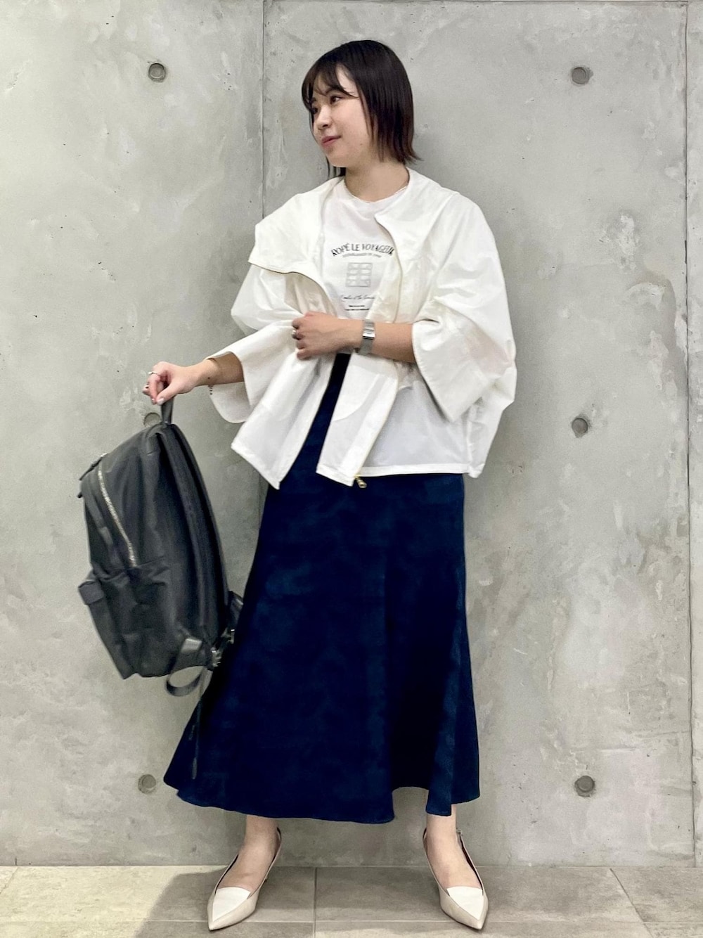 ベージュ系のパンプス、ブルー系のスカート、ホワイト系のマウンテンパーカーを着用したレディースの春コーディネートの1枚目の写真