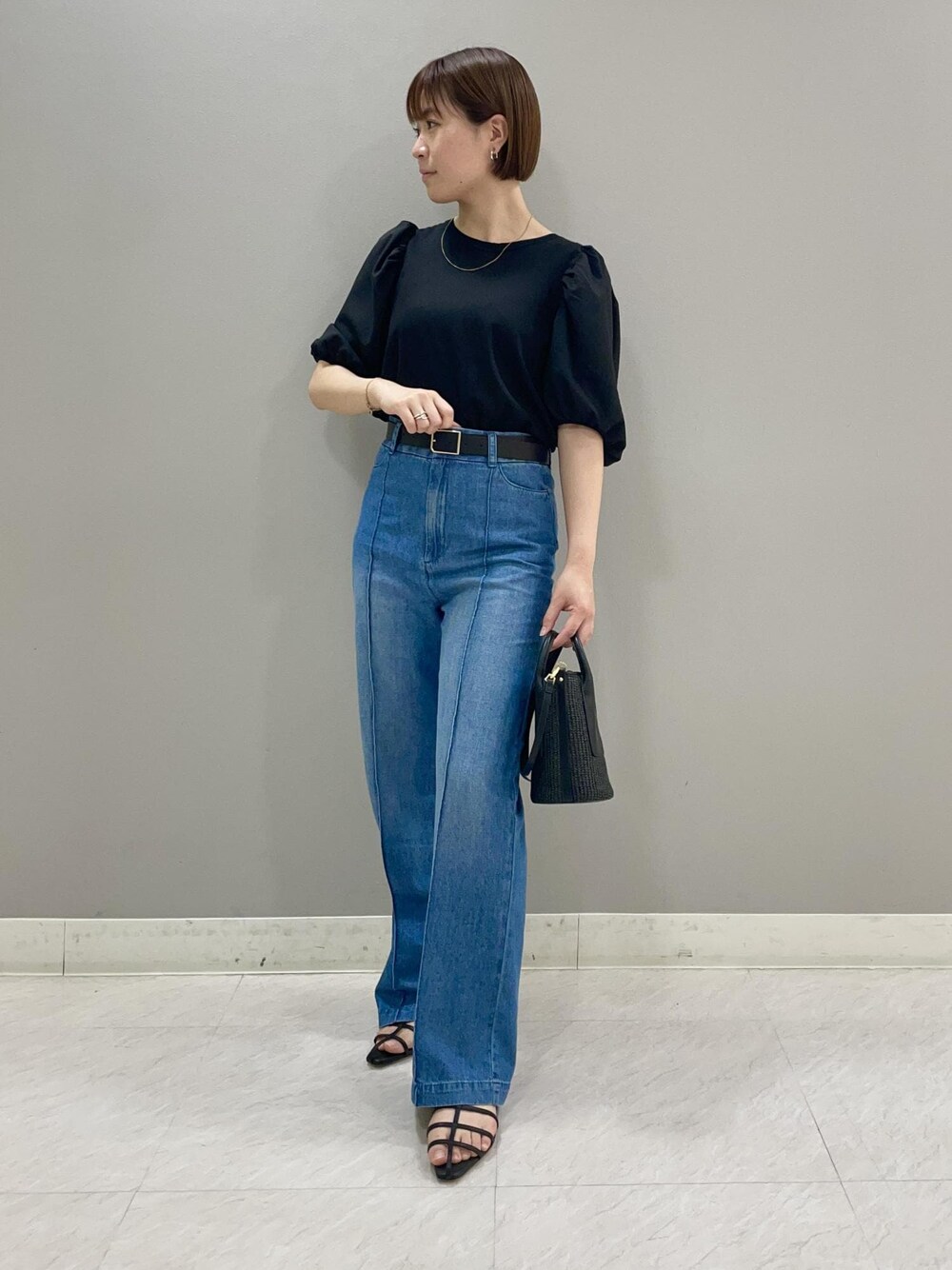 ブラック系のサンダル、ブラック系のハンドバッグ、ブラック系のTシャツ/カットソーを着用したレディースの夏コーディネートの1枚目の写真