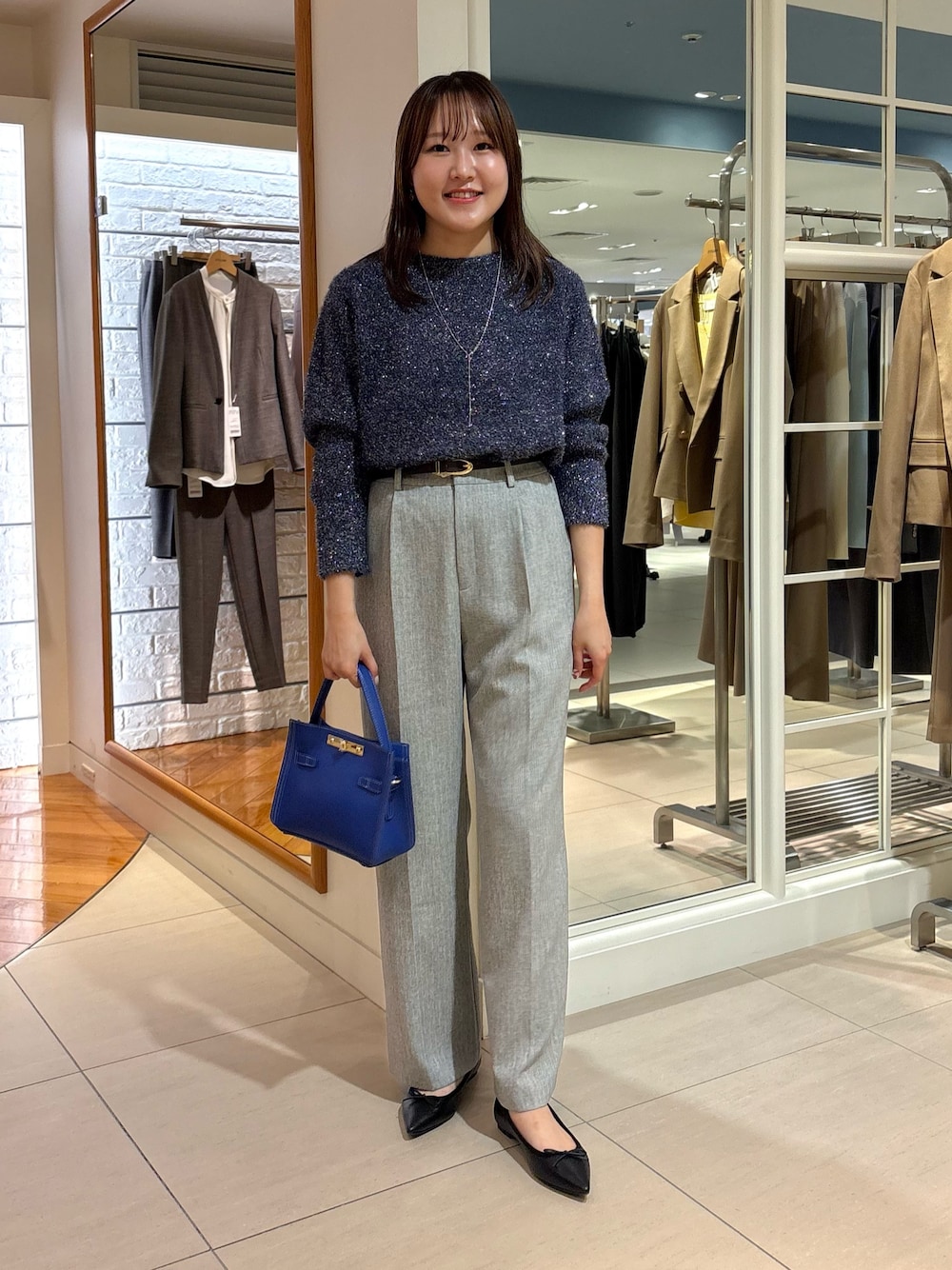 グレー系のその他パンツ、ブルー系のニット/セーター、ブルー系のショルダーバッグを着用したレディースの冬コーディネートの1枚目の写真