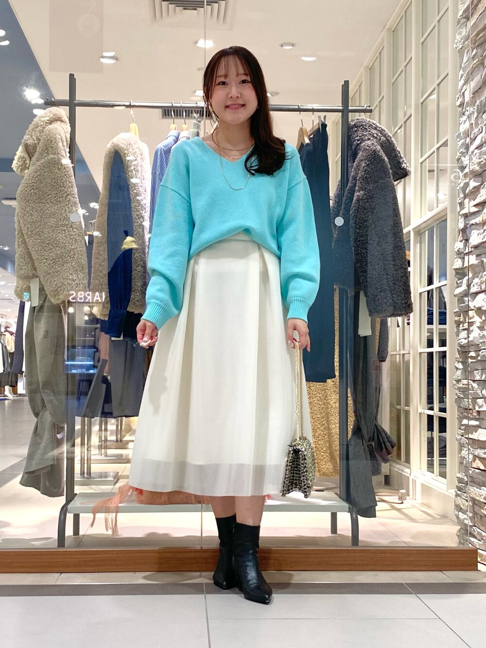 ホワイト系のスカート、グリーン系のニット/セーター、その他のショルダーバッグを着用したレディースの冬コーディネートの1枚目の写真