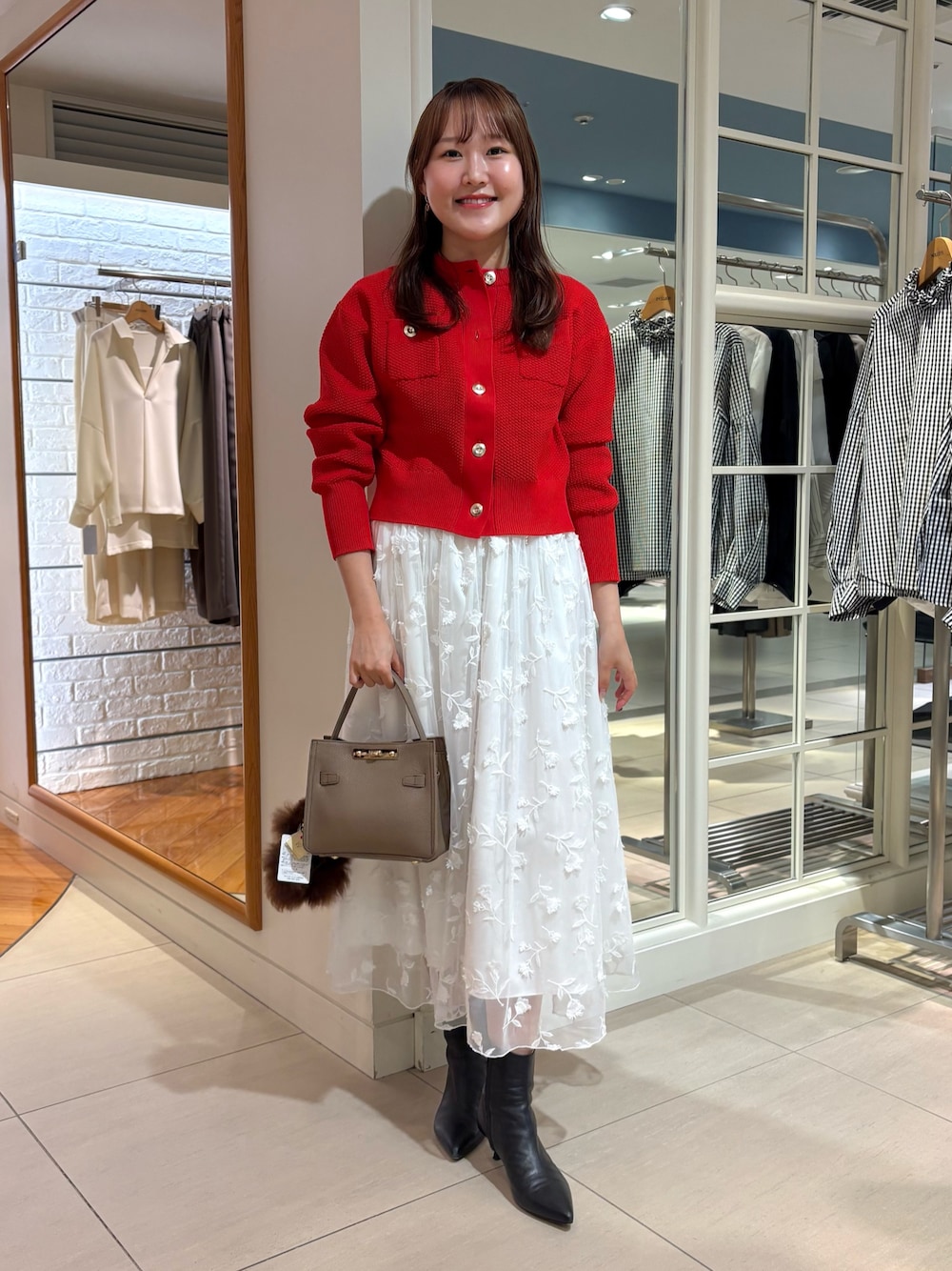 ホワイト系のスカート、レッド系のカーディガン/ボレロ、ベージュ系のショルダーバッグを着用したレディースの秋コーディネートの1枚目の写真