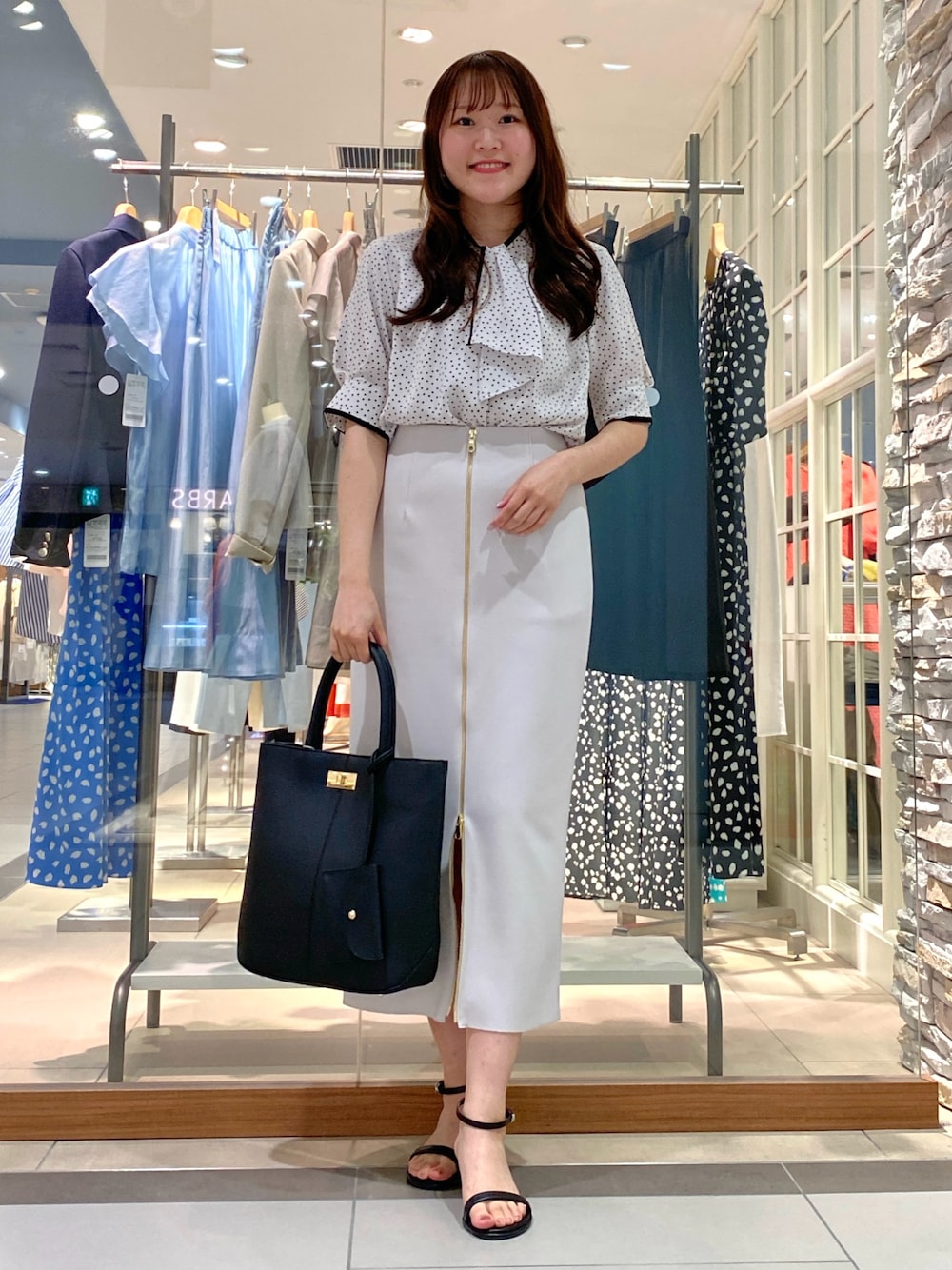 ホワイト系のシャツ/ブラウス、ホワイト系のスカート、ブラック系のトートバッグを着用したレディースの夏コーディネートの1枚目の写真