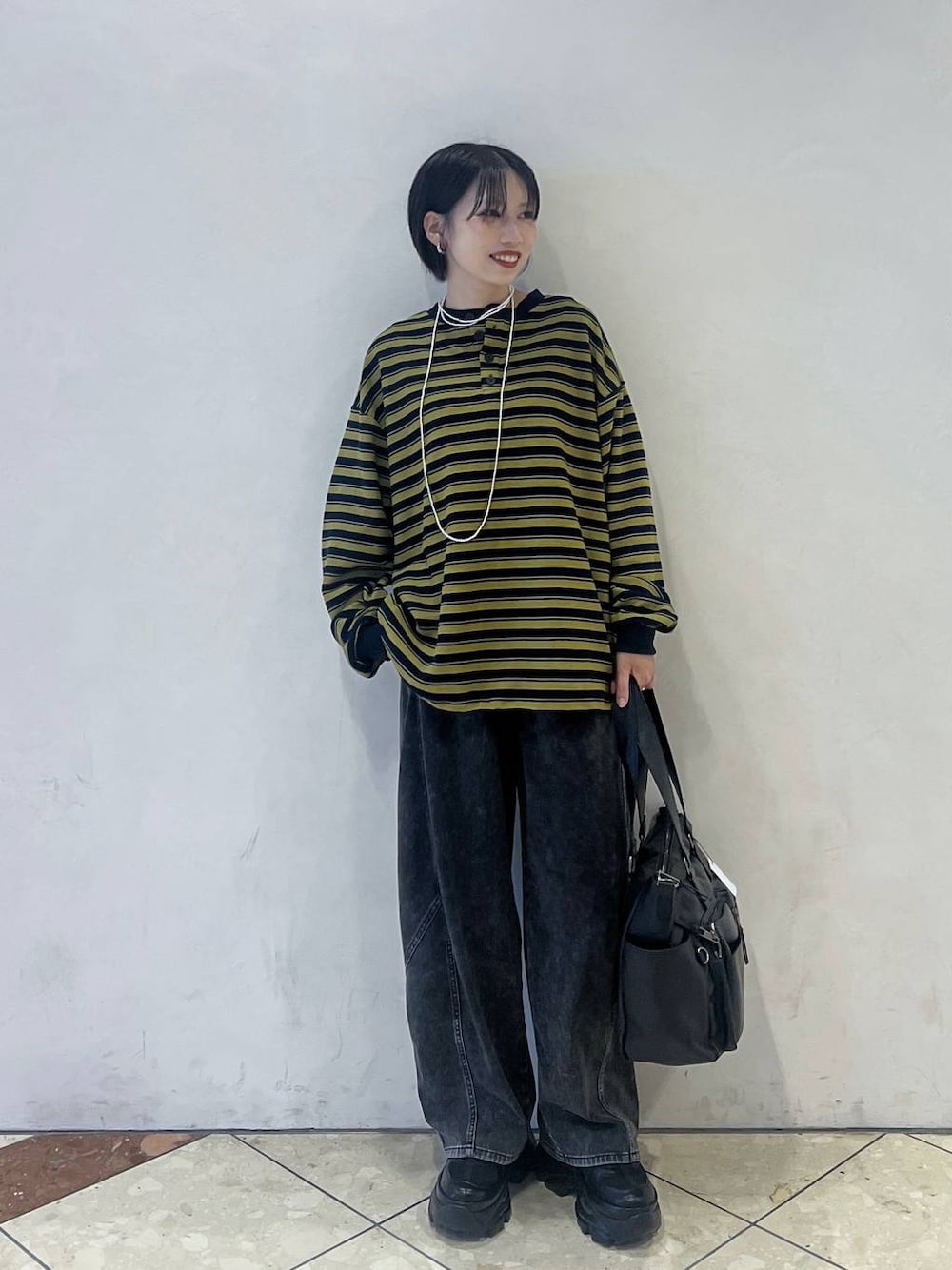 ブラック系のスニーカー、ブルー系のTシャツ/カットソー、ブラック系のボストンバッグを着用したレディースの秋コーディネートの1枚目の写真