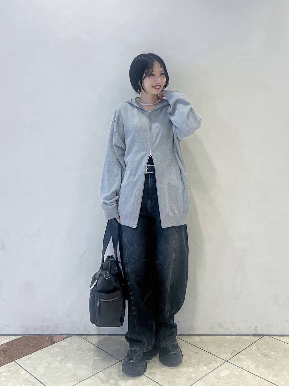 グレー系のパーカー、ブルー系のデニムパンツ、ブラック系のスニーカーを着用したレディースの秋コーディネートの1枚目の写真
