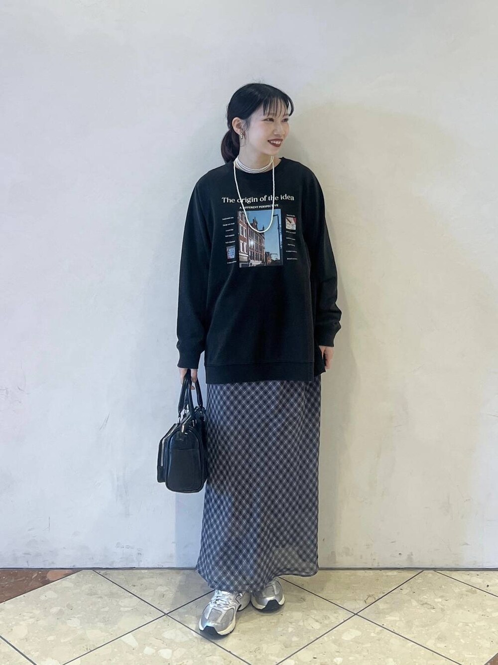 ブラック系のショルダーバッグ、グレー系のスカート、グレー系のTシャツ/カットソーを着用したレディースの春コーディネートの1枚目の写真