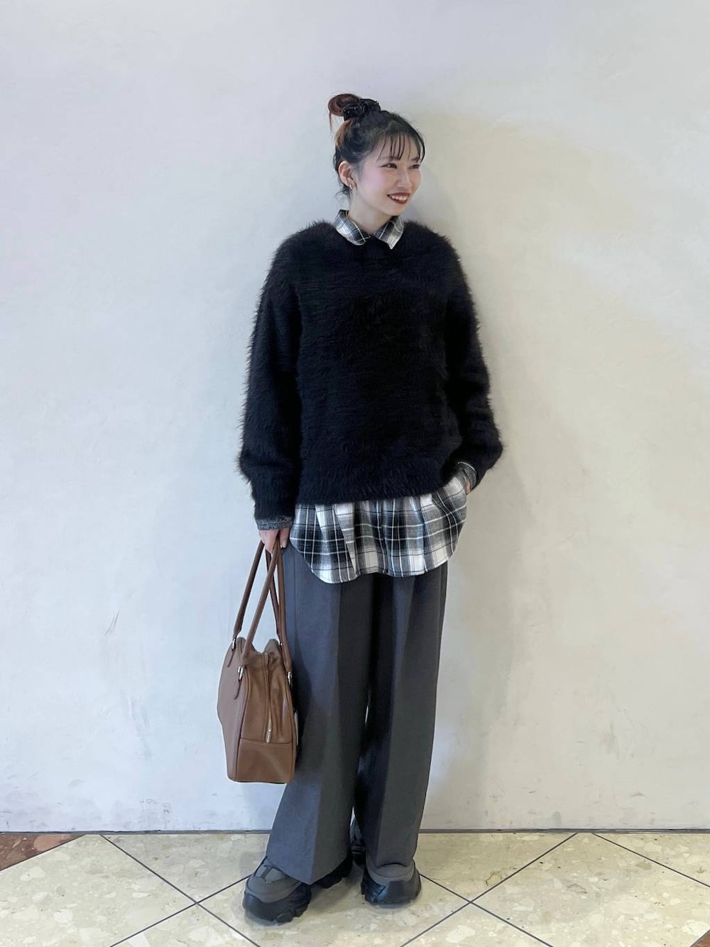 グレー系のスニーカー、イエロー系のボストンバッグ、ブラック系のニット/セーターを着用したレディースの秋コーディネートの1枚目の写真