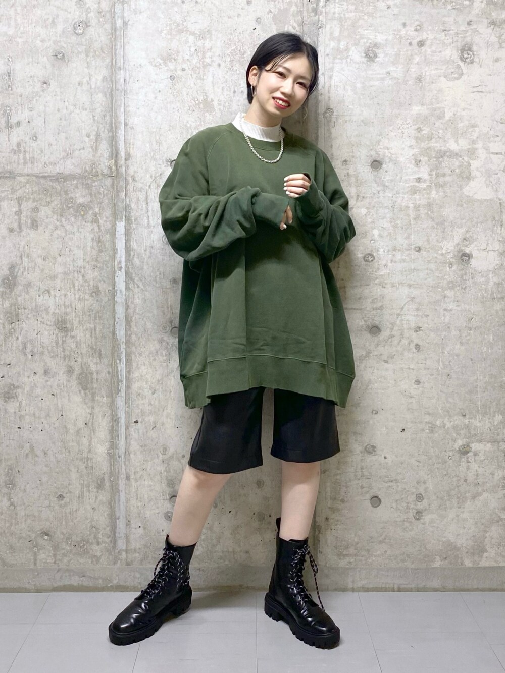 ブラック系のブーツ、グリーン系のスウェット、ブラック系のその他パンツを着用したレディースの冬コーディネートの1枚目の写真