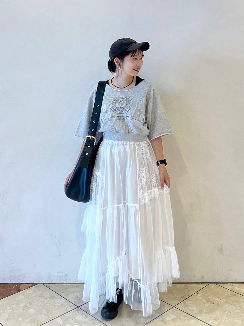 ブラック系のショルダーバッグ、ホワイト系のスカート、グレー系のTシャツ/カットソーを着用したレディースの夏コーディネートの1枚目の写真