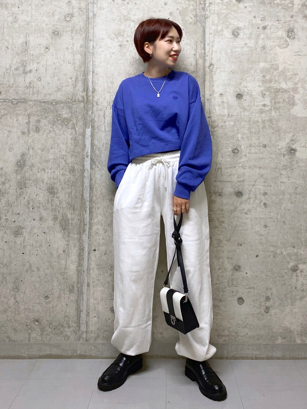 パープル系のスウェット、ブラック系のタンクトップ、ホワイト系のスウェットパンツを着用したレディースの秋コーディネートの1枚目の写真