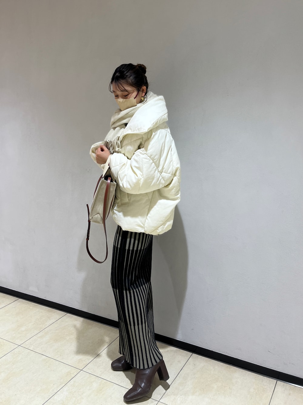 ホワイト系のダウンジャケット/コート、ベージュ系のショルダーバッグ、ブラック系のスカートを着用したレディースの冬コーディネートの1枚目の写真