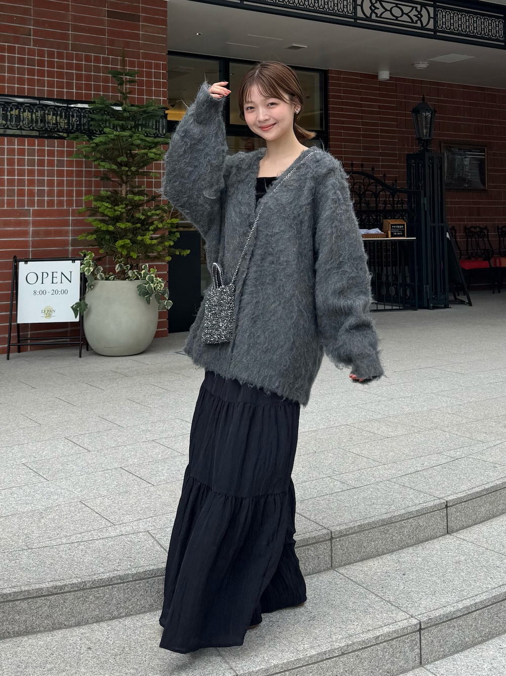 ブラック系のスカート、グレー系のカーディガン/ボレロ、ブラック系のドレスシューズを着用したレディースの秋コーディネートの1枚目の写真