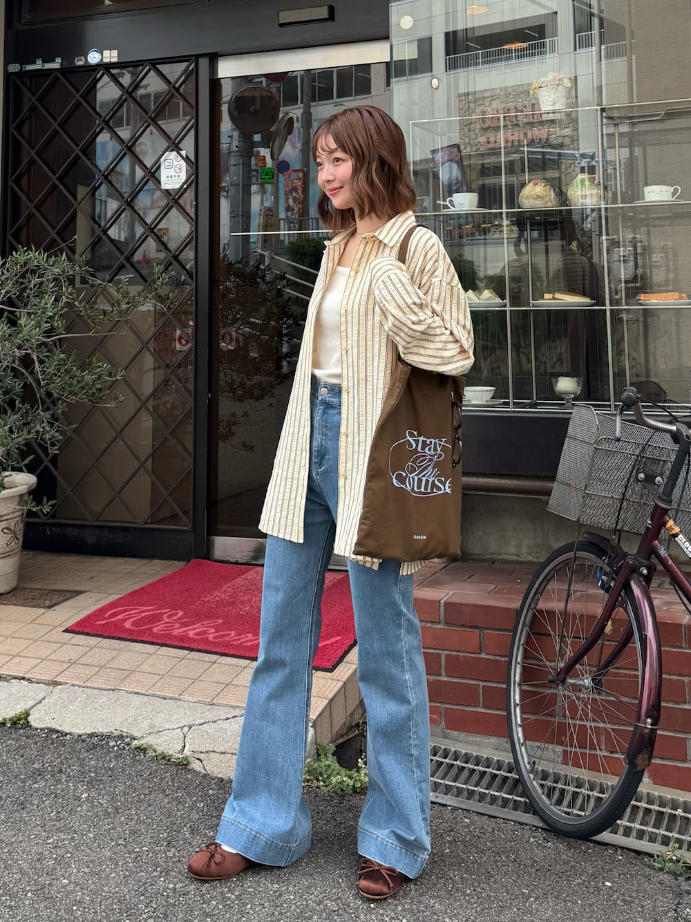 イエロー系のシャツ/ブラウス、ブラウン系のトートバッグ、ブラウン系のドレスシューズを着用したレディースの秋コーディネートの1枚目の写真