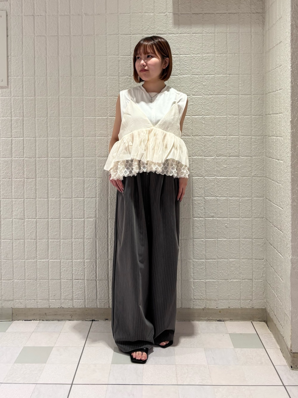 ホワイト系のその他トップス、グレー系のその他パンツ、ブラック系のサンダルを着用したレディースの春コーディネートの1枚目の写真
