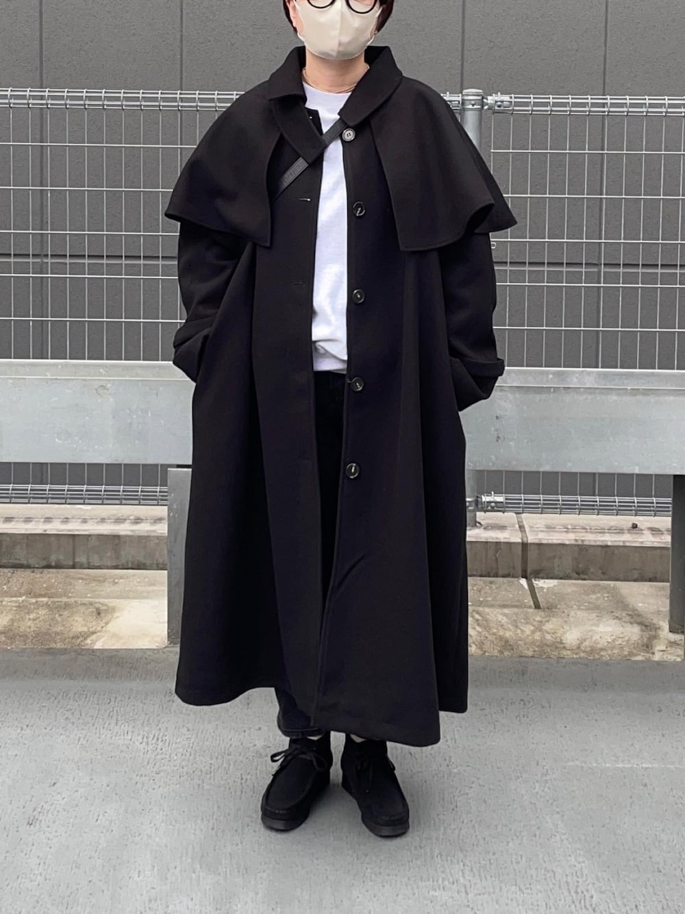 ブラック系のステンカラーコート、ブラック系のブーツを着用したレディースの秋コーディネートの1枚目の写真