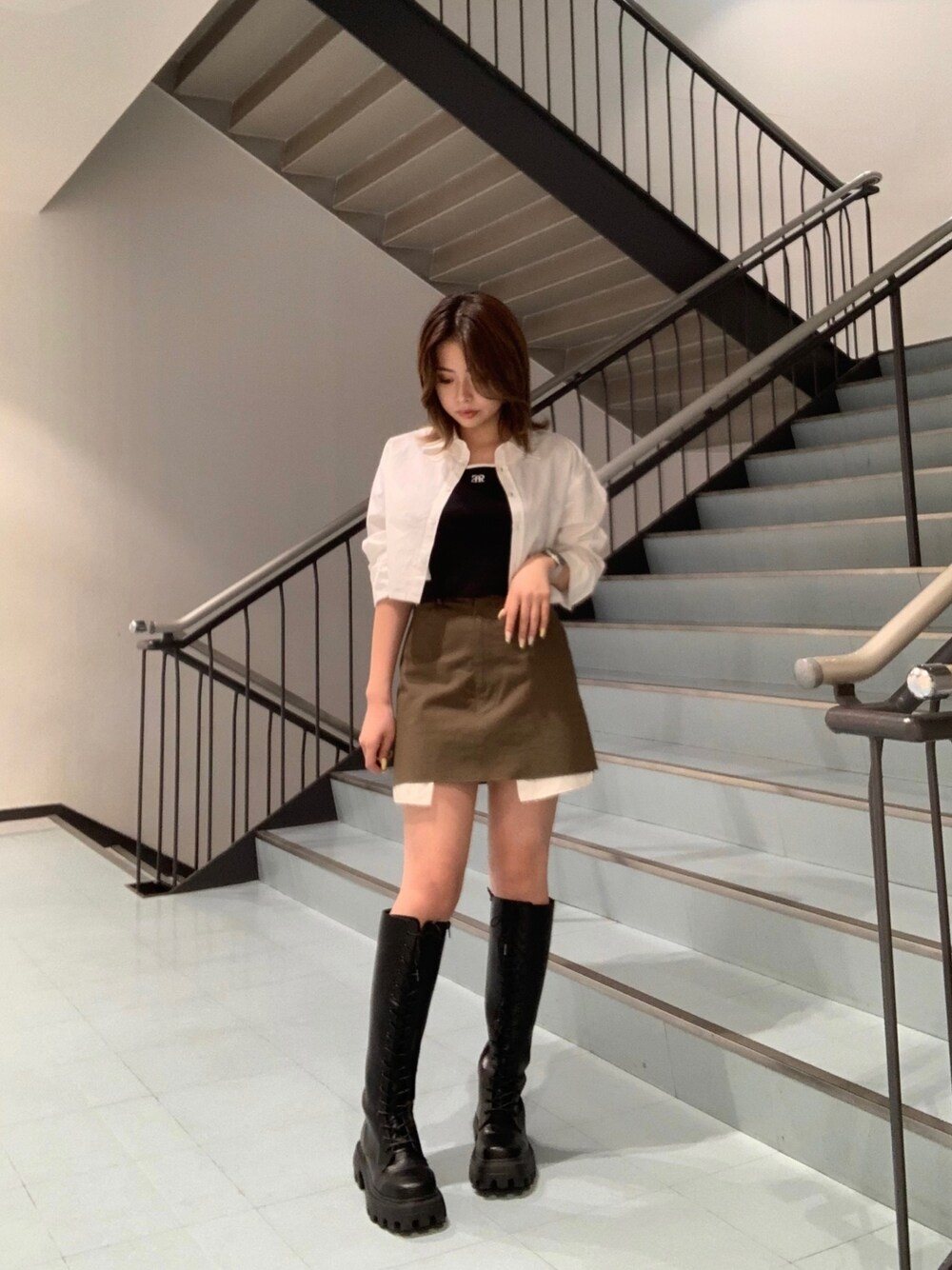 ブラック系のTシャツ/カットソー、ホワイト系のシャツ/ブラウス、グリーン系のスカートを着用したレディースの春コーディネートの1枚目の写真