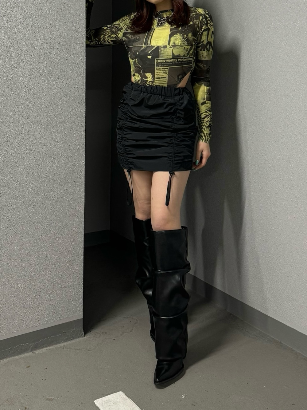 イエロー系のTシャツ/カットソー、ブラック系のスカート、ブラック系のブーツを着用したレディースの冬コーディネートの1枚目の写真