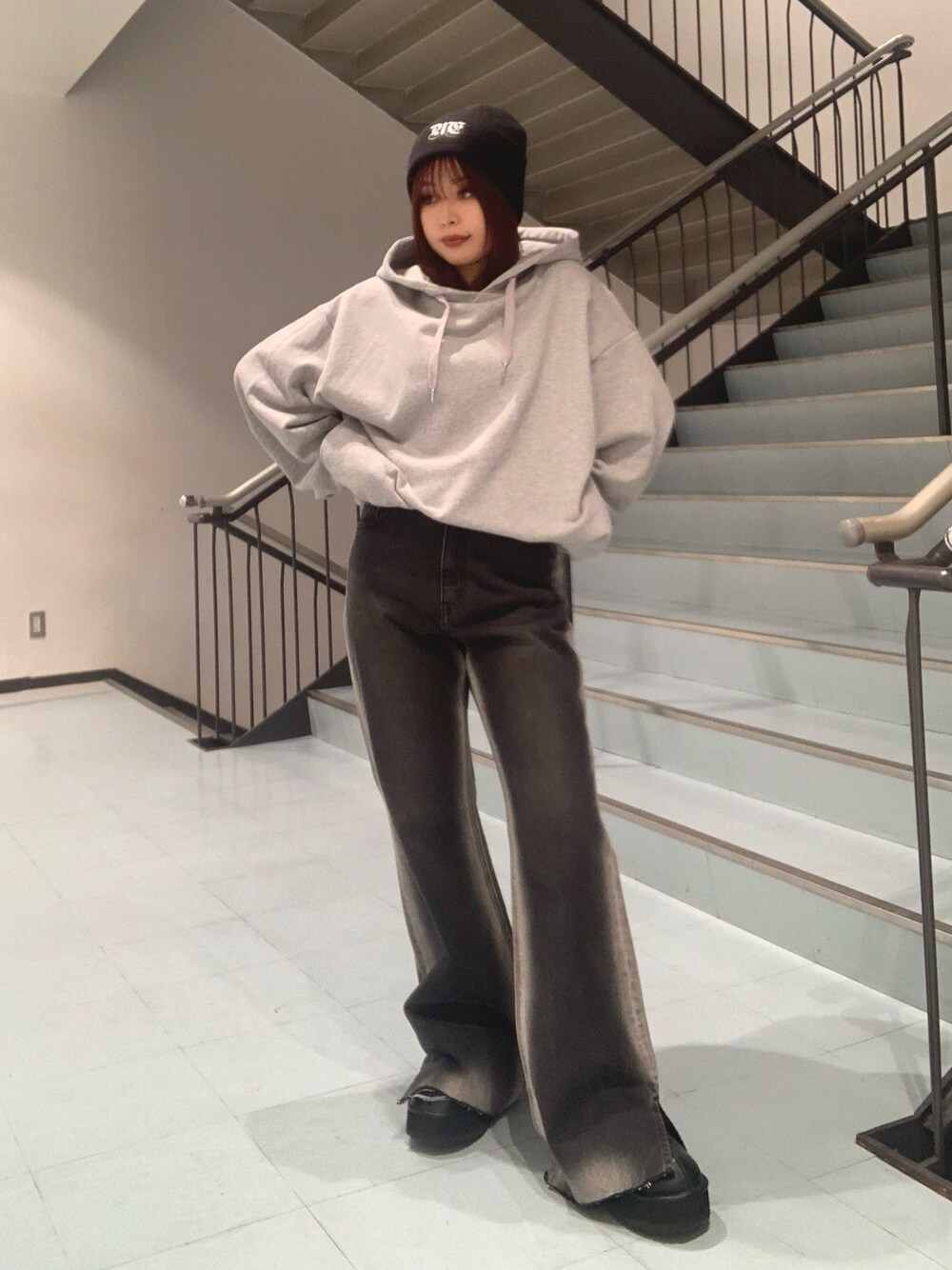 グレー系のパーカー、ブラック系のデニムパンツ、ブラック系のスリッポンを着用したレディースの秋コーディネートの1枚目の写真