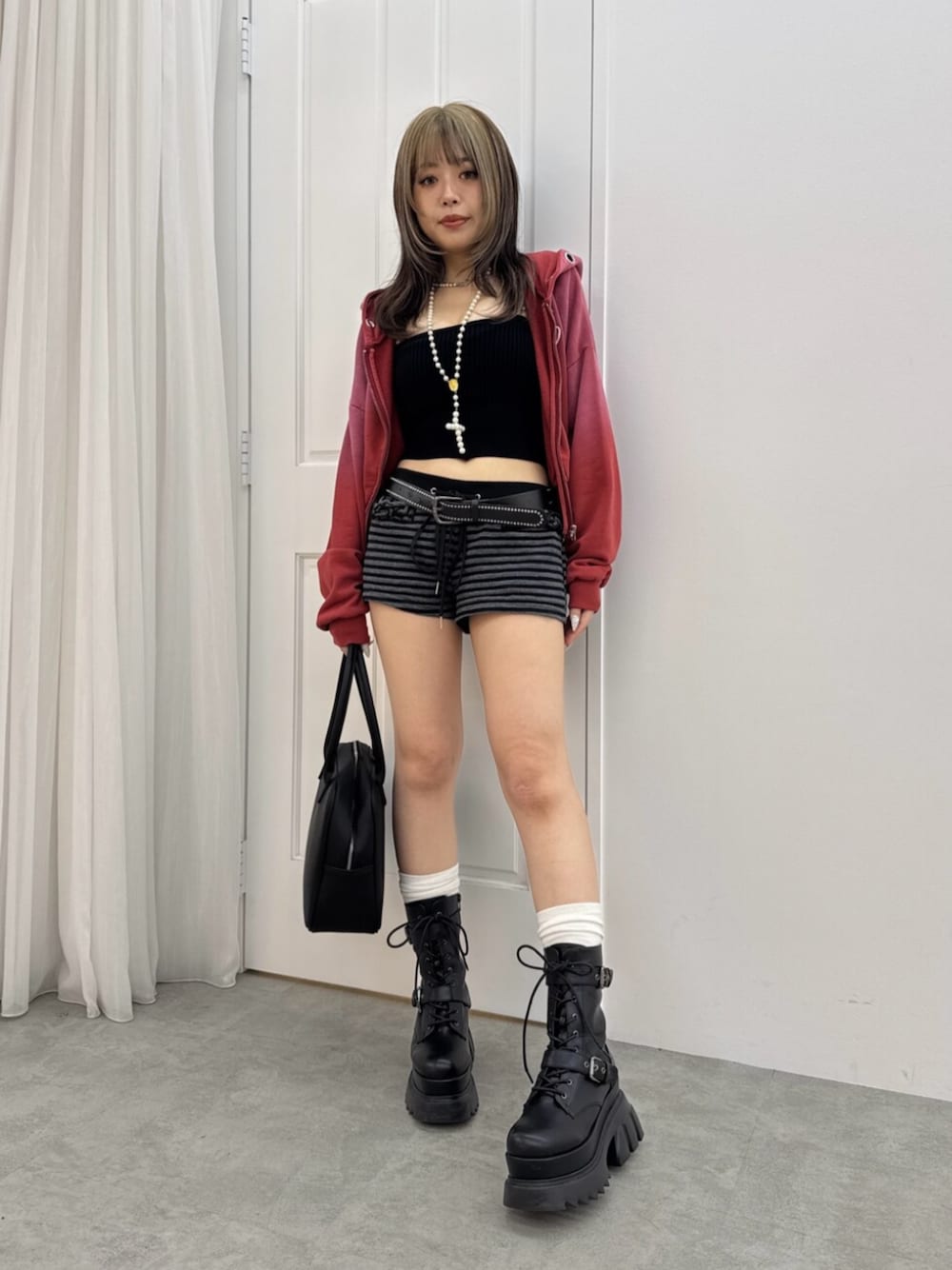 ブラック系のボストンバッグ、レッド系のパーカー、ブラック系のブーツを着用したレディースの夏コーディネートの1枚目の写真