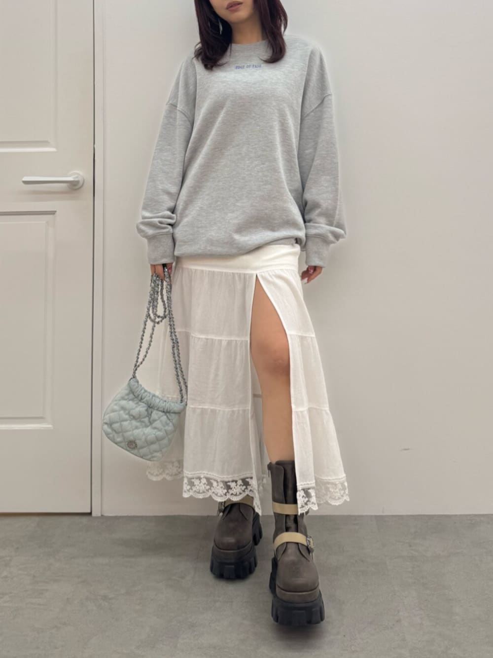 ブラウン系のブーツ、グレー系のスウェット、ホワイト系のスカートを着用したレディースの冬コーディネートの1枚目の写真