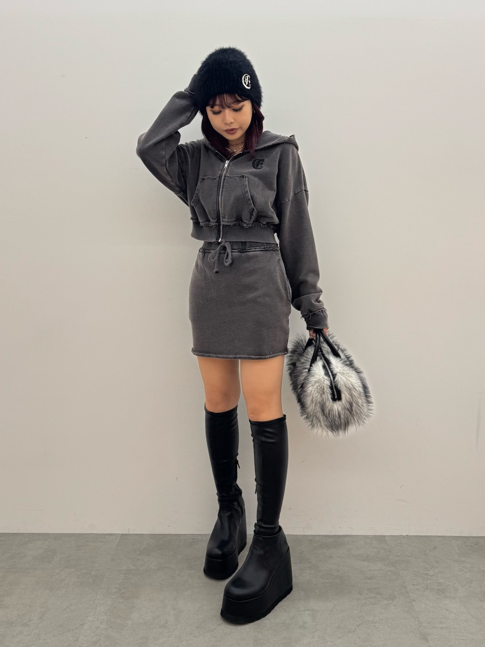 ブラック系のパーカー、ブラック系のスカート、ブラック系のボストンバッグを着用したレディースの秋コーディネートの1枚目の写真