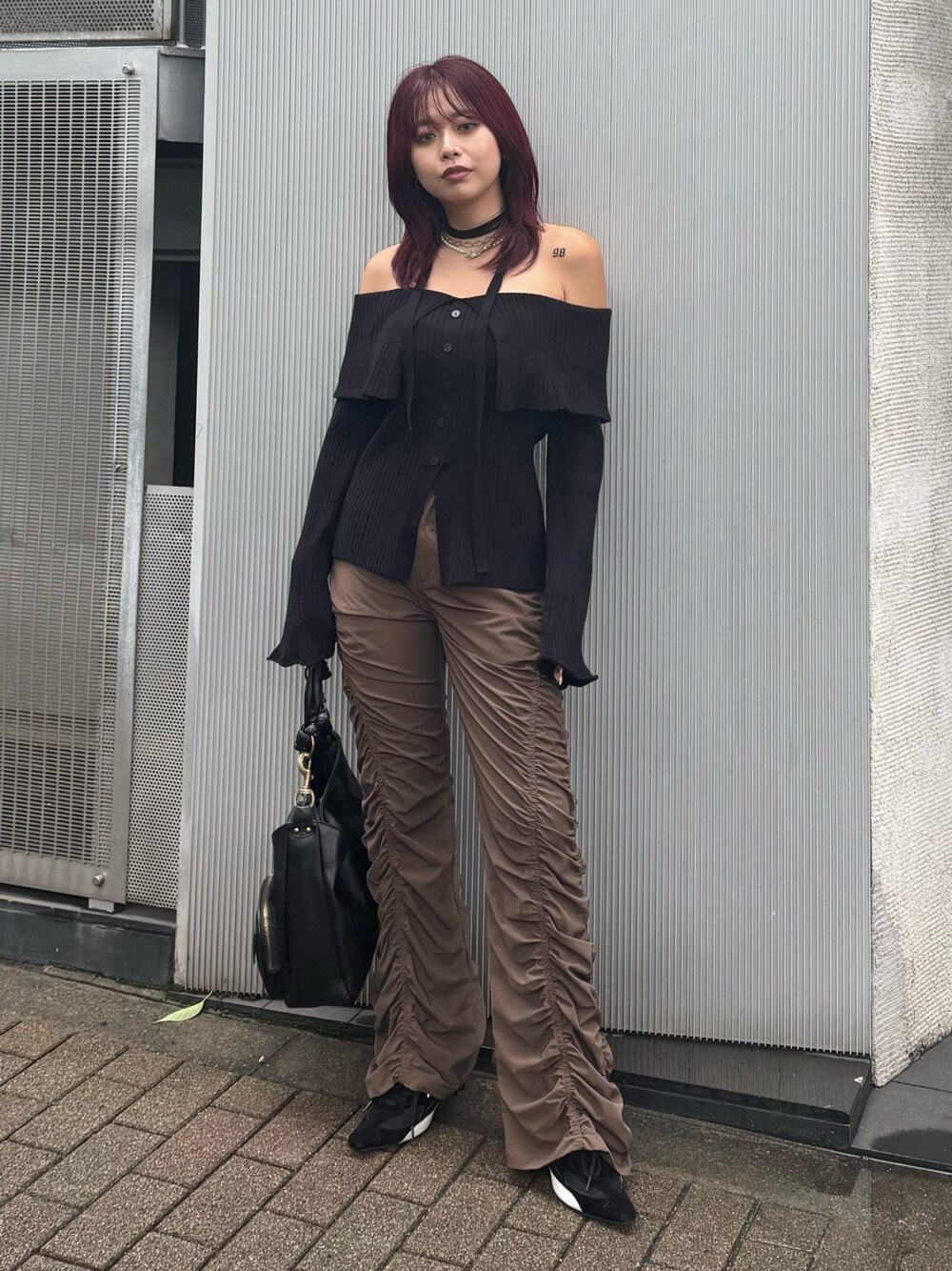 ブラック系のニット/セーター、ブラウン系のその他パンツ、ブラック系のハンドバッグを着用したレディースの夏コーディネートの1枚目の写真