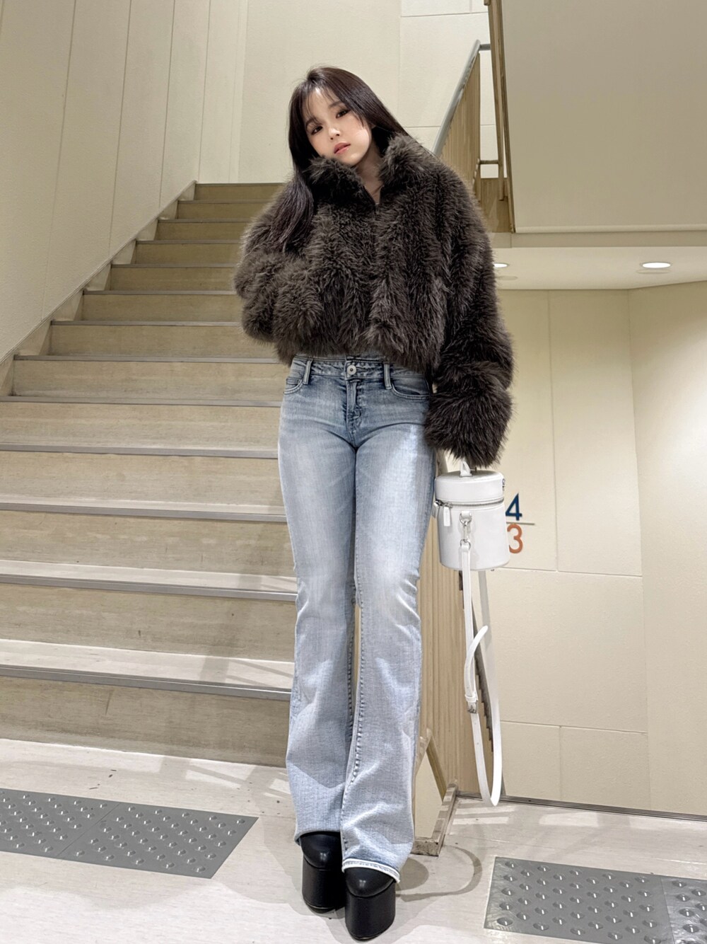 ブラウン系のその他アウター、ブルー系のデニムパンツ、ホワイト系のハンドバッグを着用したレディースの冬コーディネートの1枚目の写真