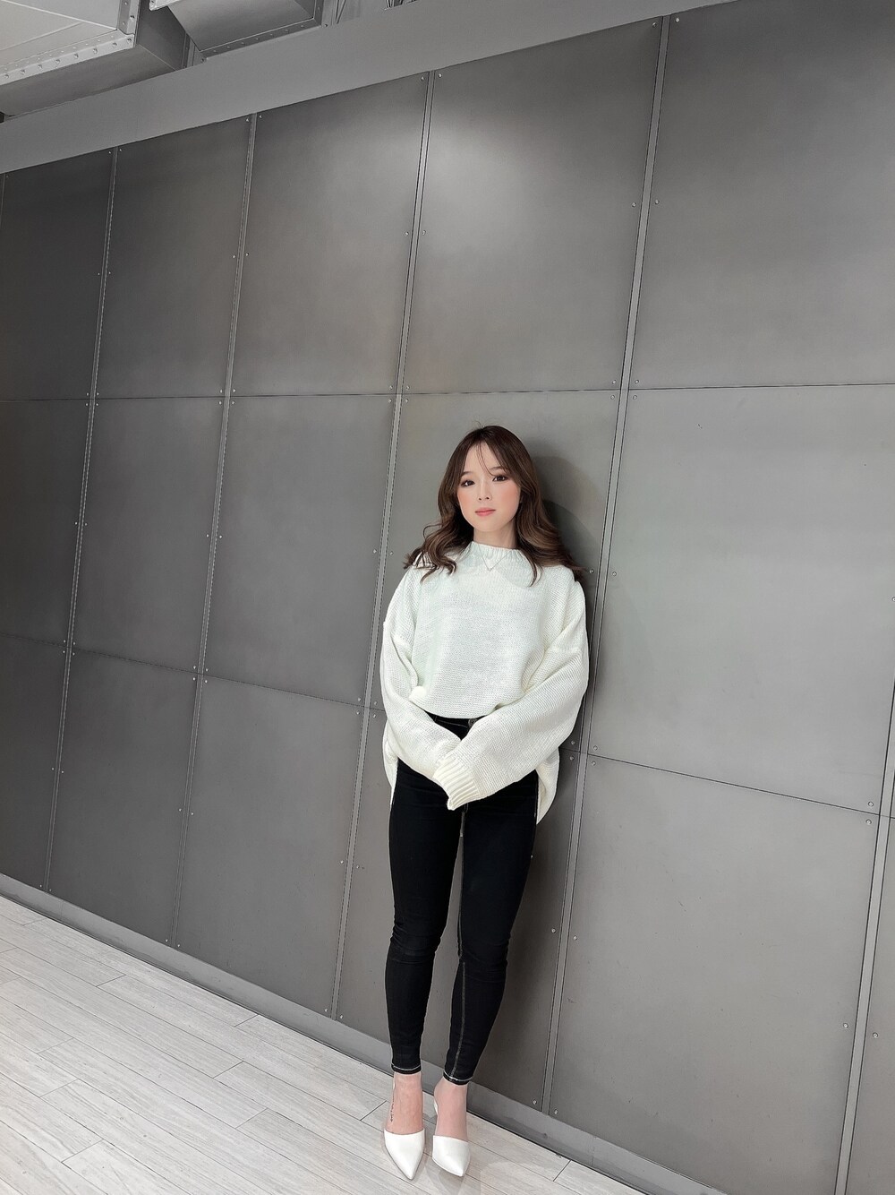 ホワイト系のニット/セーター、ブラック系のデニムパンツ、ホワイト系のパンプスを着用したレディースの冬コーディネートの1枚目の写真