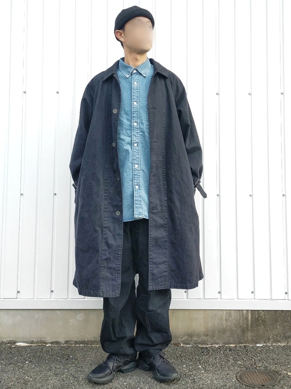 ブラック系のステンカラーコート、ブルー系のシャツ/ブラウス、ブラック系のスニーカーを着用したメンズの春コーディネートの2枚目の写真