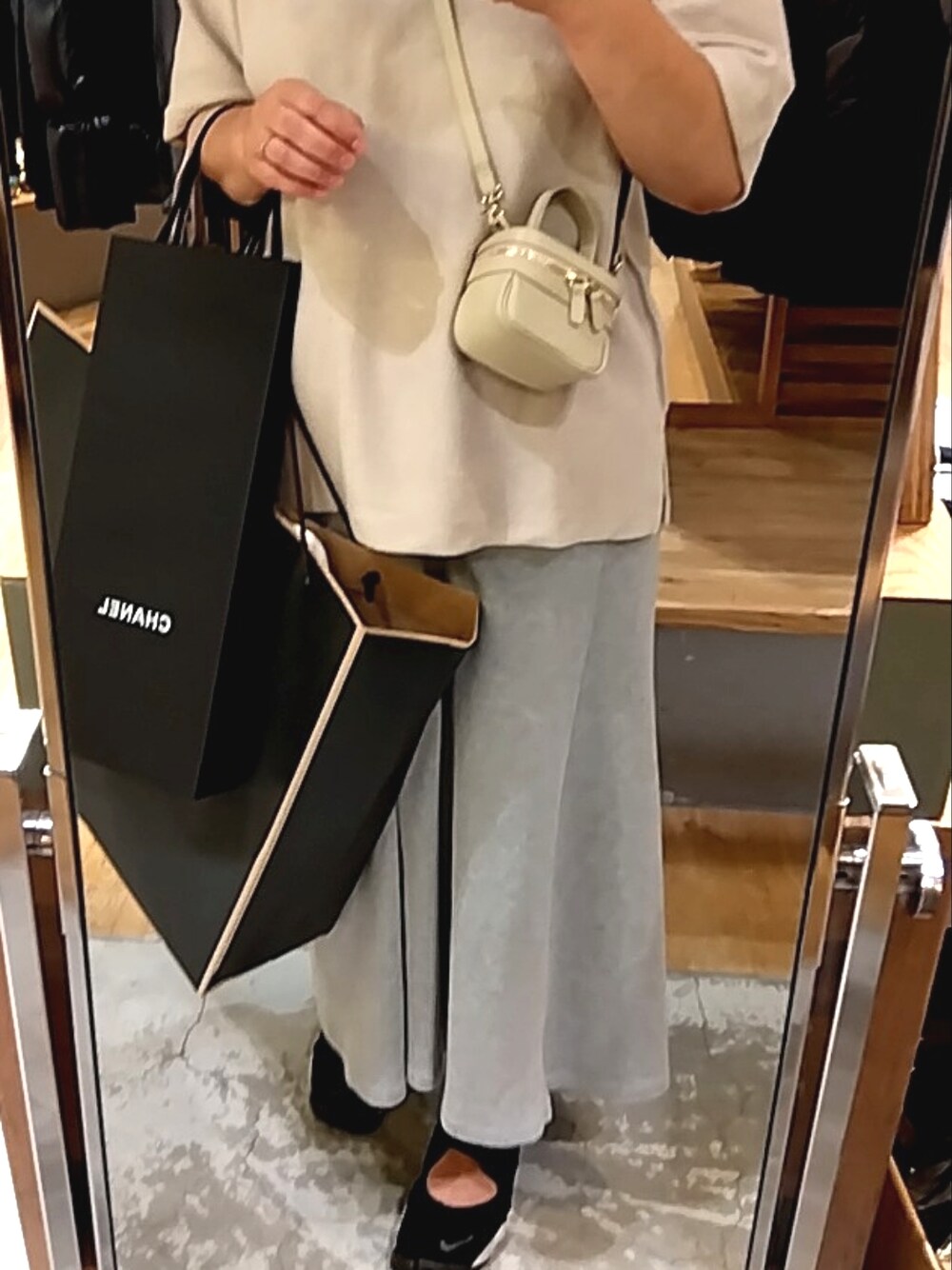 ベージュ系のショルダーバッグ、グレー系のスカート、ブラック系のスニーカーを着用したレディースの夏コーディネートの1枚目の写真