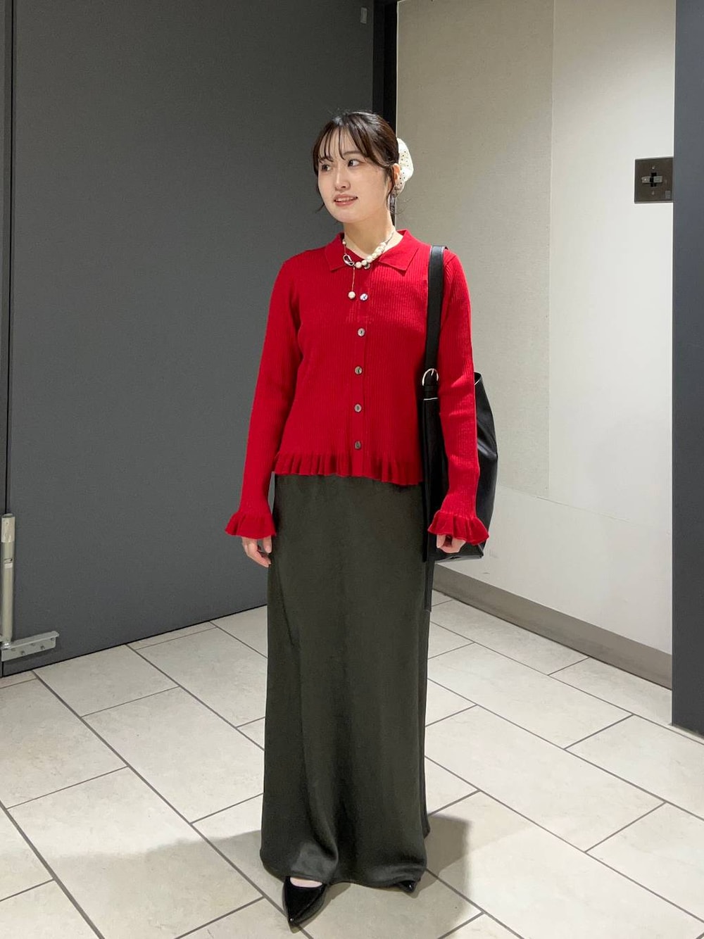 グレー系のスカート、レッド系のニット/セーター、ブラック系のパンプスを着用したレディースの秋コーディネートの1枚目の写真