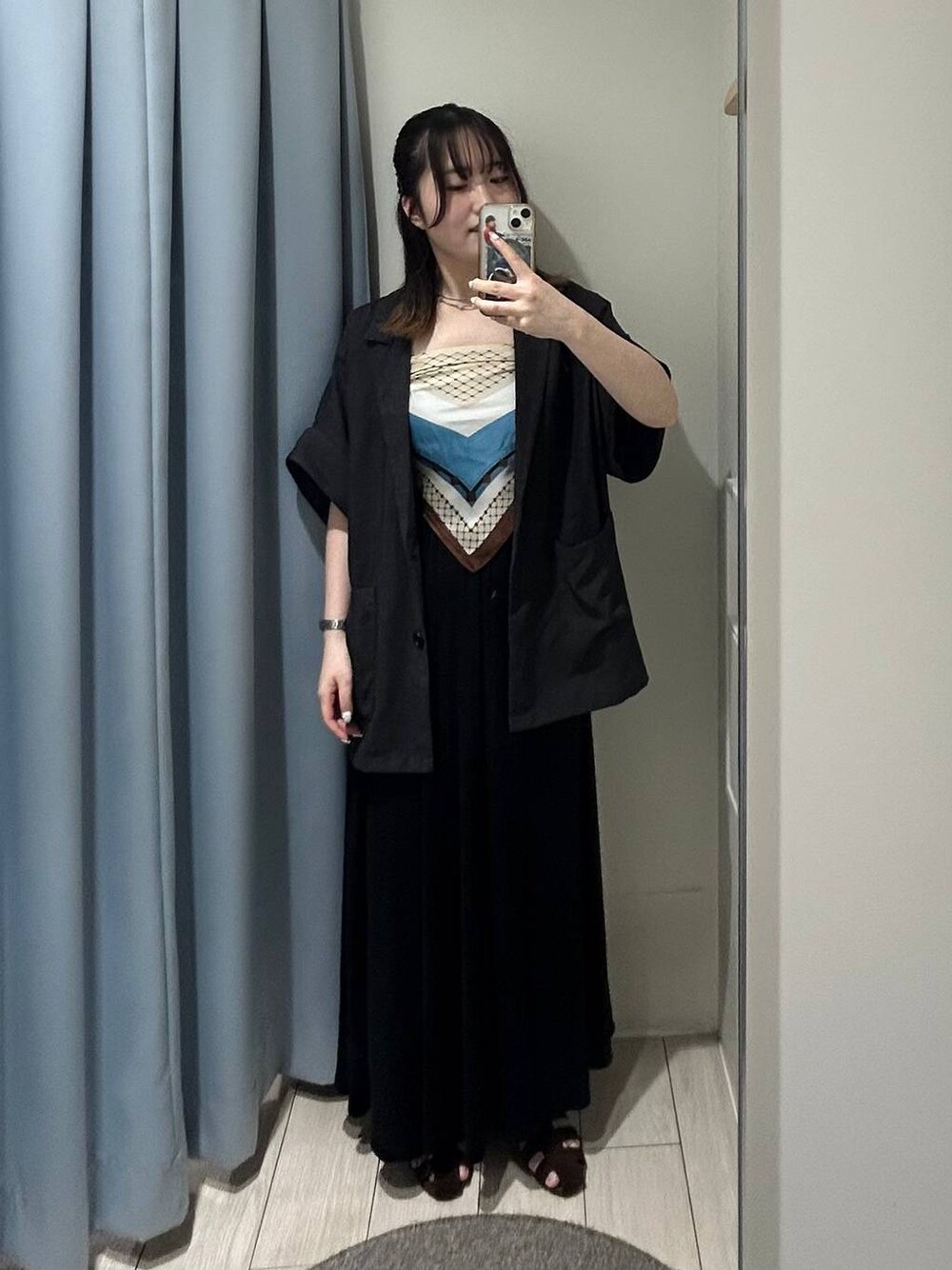 グレー系のテーラードジャケット、ブラウン系のサンダル、ブラック系のスカートを着用したレディースの夏コーディネートの1枚目の写真