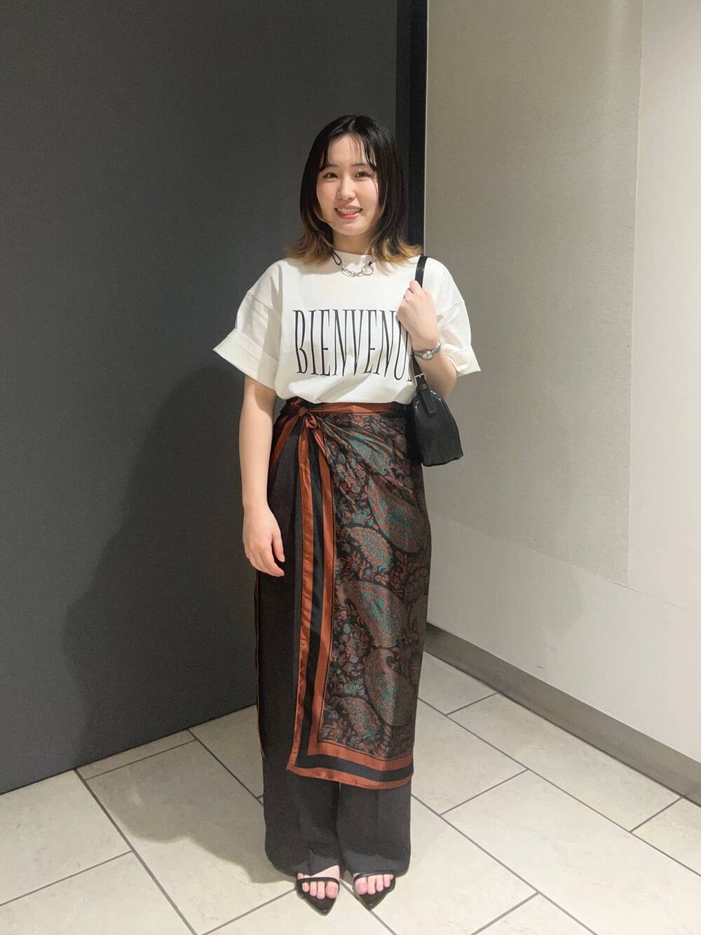 ブラック系のサンダル、ホワイト系のTシャツ/カットソー、グレー系のスラックスを着用したレディースの春コーディネートの1枚目の写真