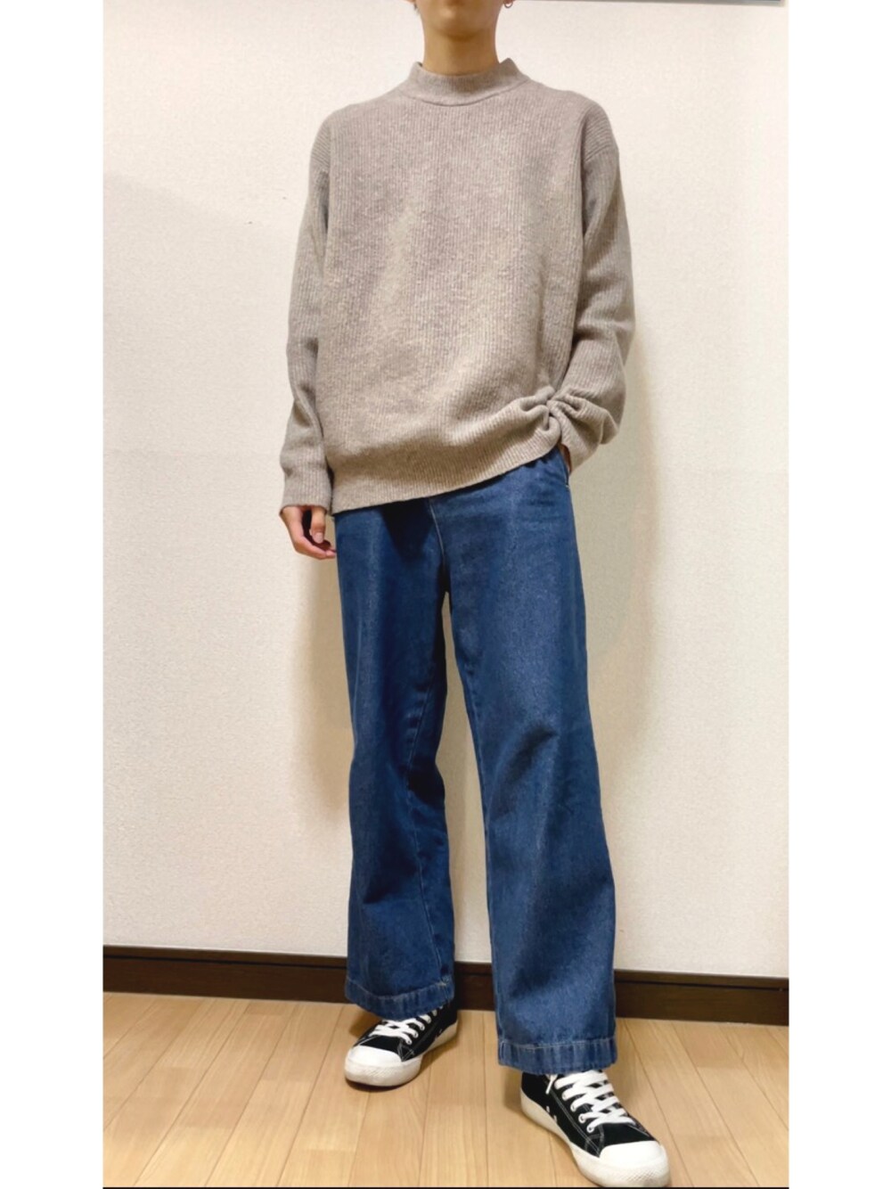 ブルー系のデニムパンツ、ベージュ系のニット/セーター、ブラック系のスニーカーを着用したメンズの秋コーディネートの1枚目の写真