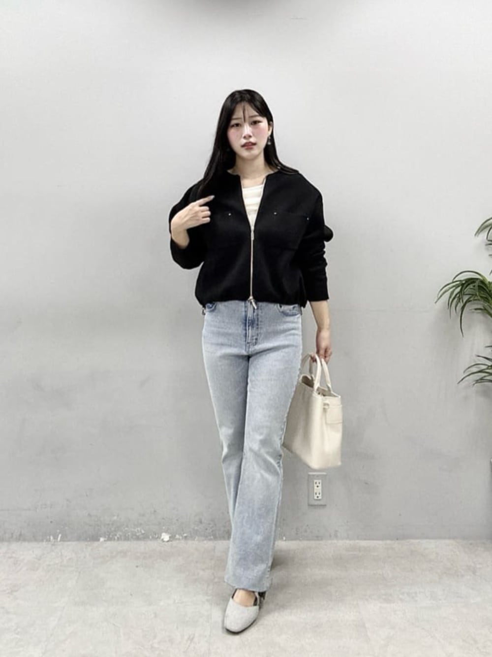 ブルー系のデニムパンツ、ホワイト系のニット/セーター、ブラック系のブルゾンを着用したレディースの春コーディネートの1枚目の写真