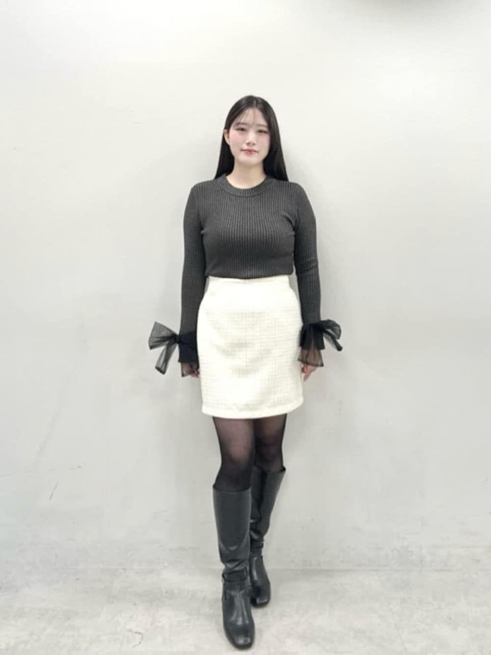 ホワイト系のスカート、グレー系のニット/セーターを着用したレディースの冬コーディネートの1枚目の写真