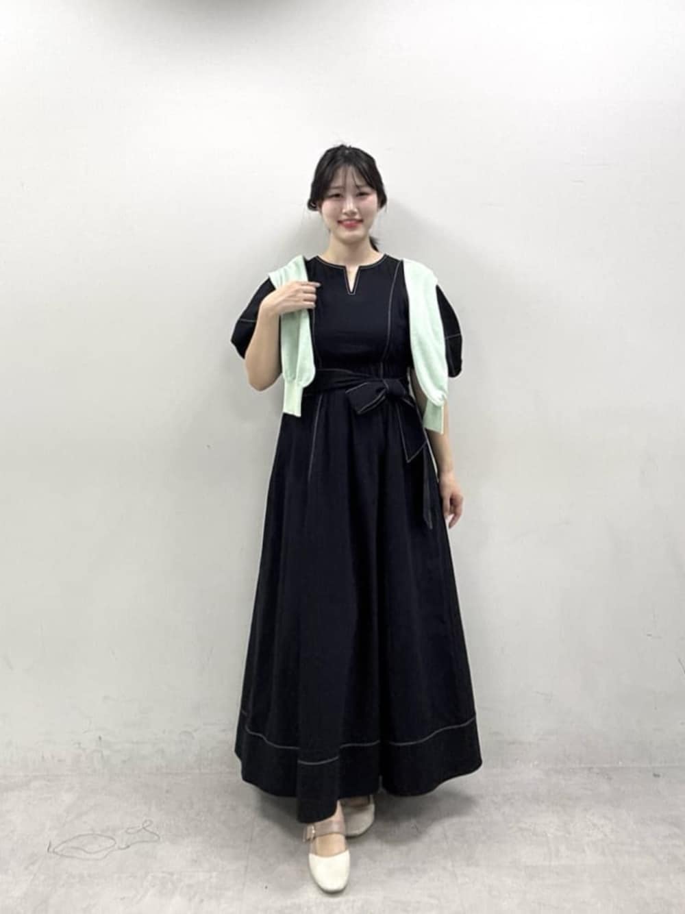 ブラック系のワンピース、グリーン系のカーディガン/ボレロを着用したレディースの春コーディネートの1枚目の写真