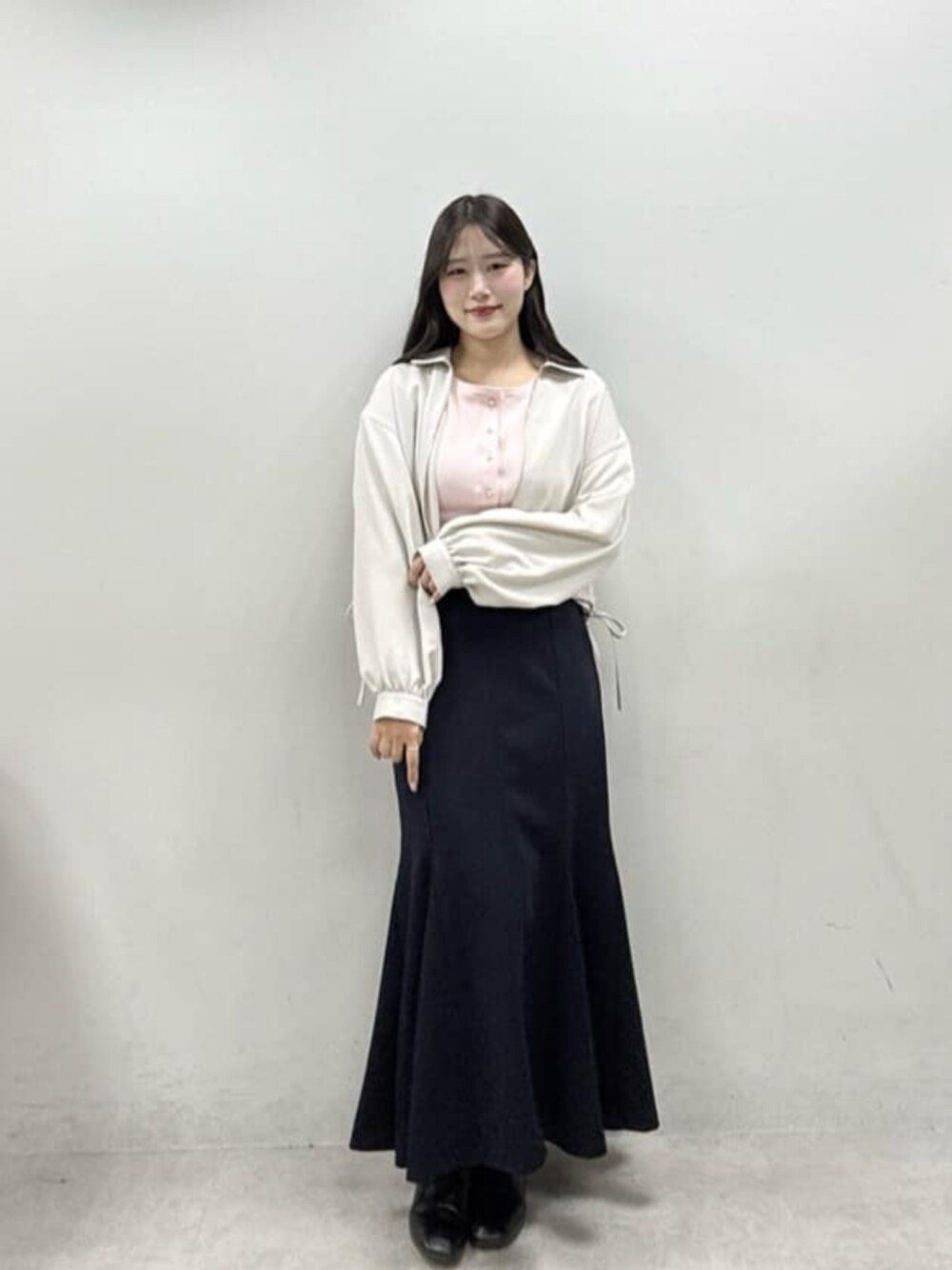 ブラック系のスカート、ホワイト系のブルゾン、ピンク系のカーディガン/ボレロを着用したレディースの冬コーディネートの1枚目の写真