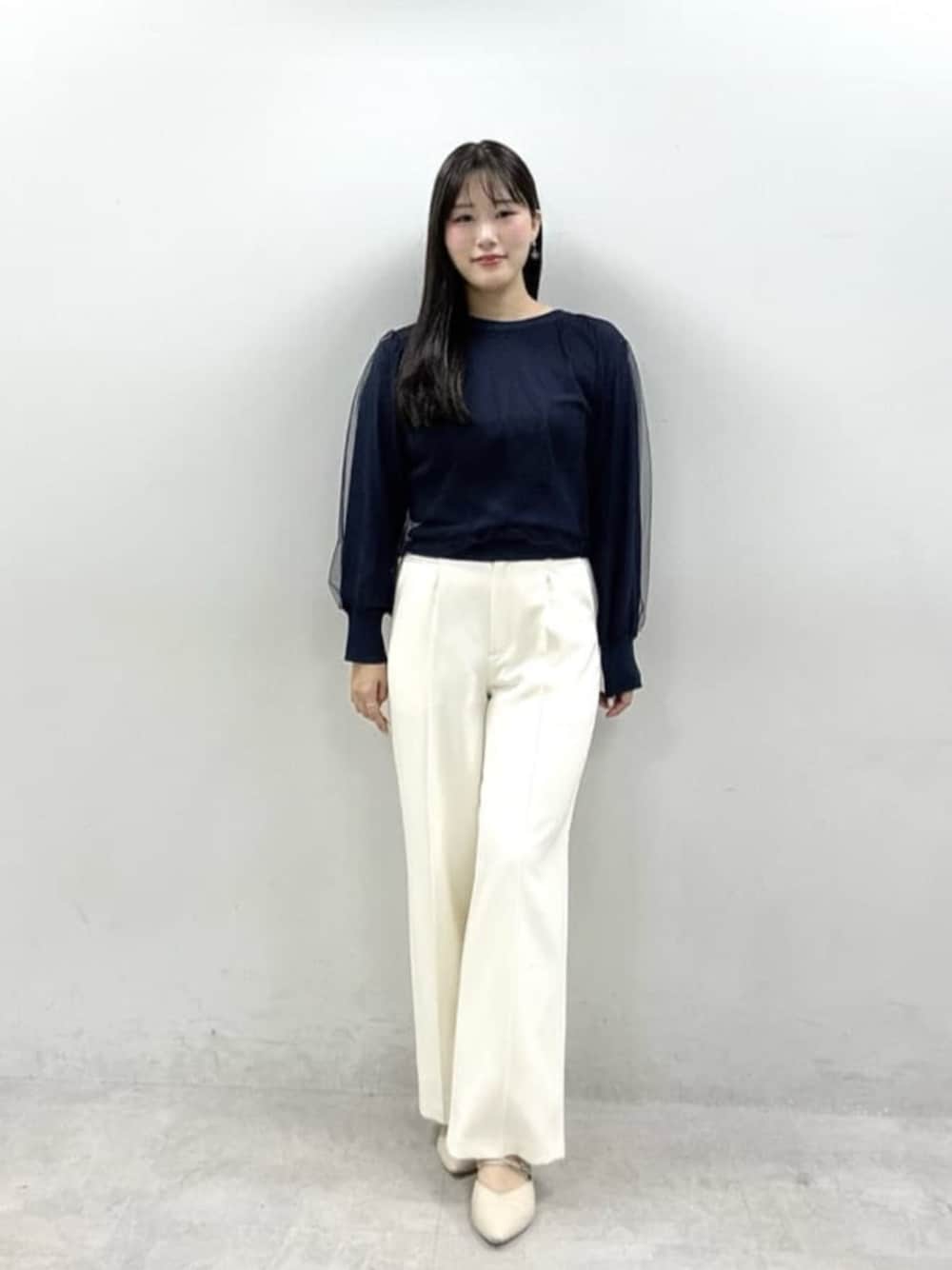 ホワイト系のスラックス、ブルー系のニット/セーターを着用したレディースの春コーディネートの1枚目の写真