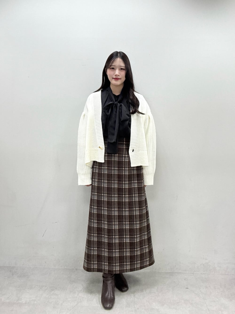 ブラック系のシャツ/ブラウス、ホワイト系のカーディガン/ボレロ、ブラウン系のスカートを着用したレディースの秋コーディネートの1枚目の写真