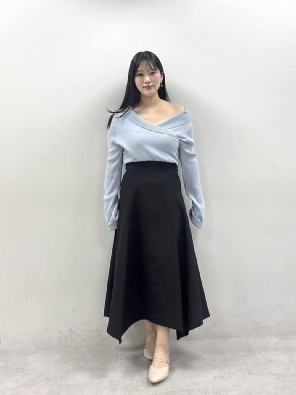 ブラック系のスカート、ブルー系のニット/セーターを着用したレディースの春コーディネートの1枚目の写真