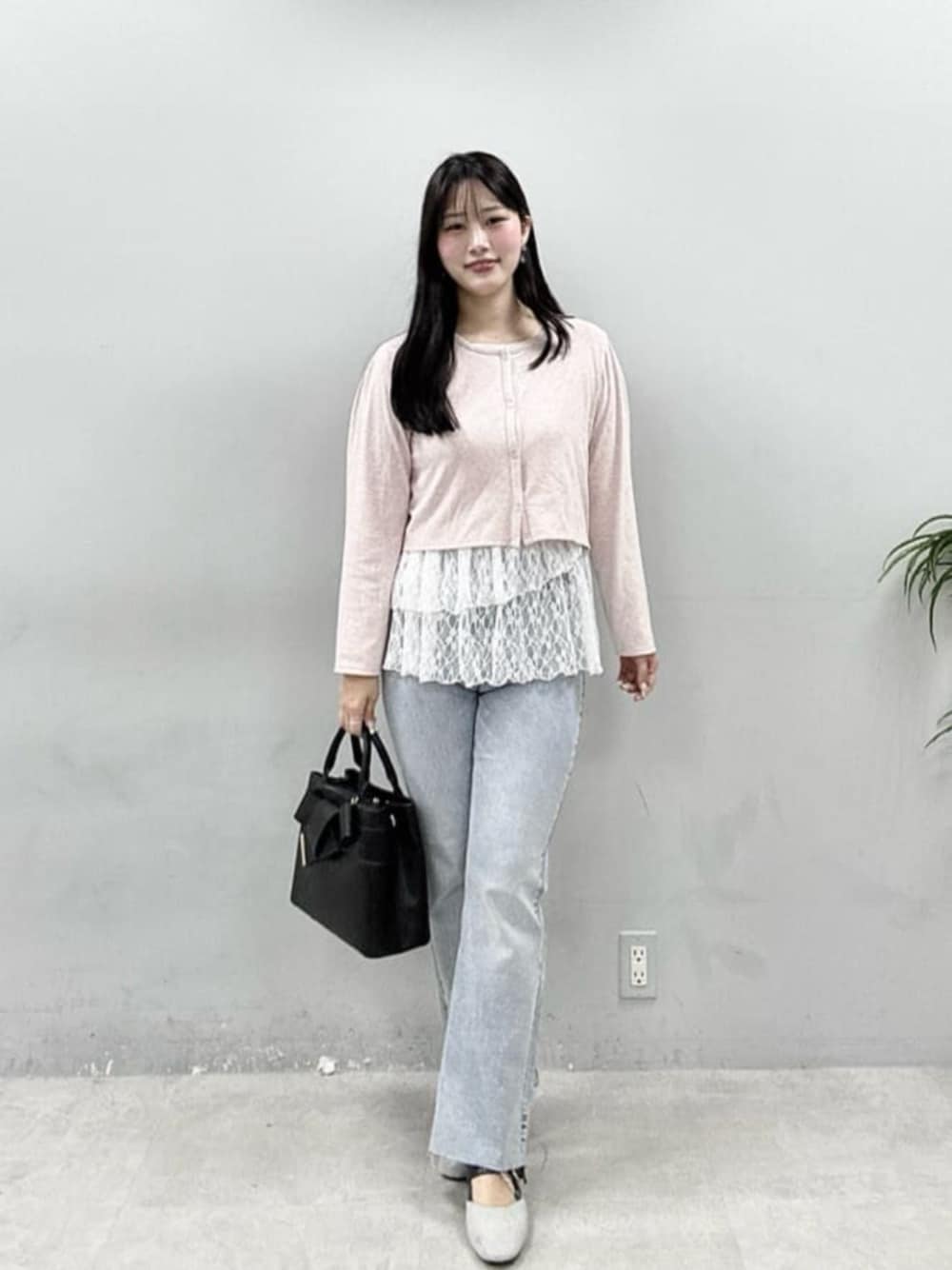 ブルー系のデニムパンツ、ピンク系のカーディガン/ボレロ、ブラック系のショルダーバッグを着用したレディースの春コーディネートの1枚目の写真