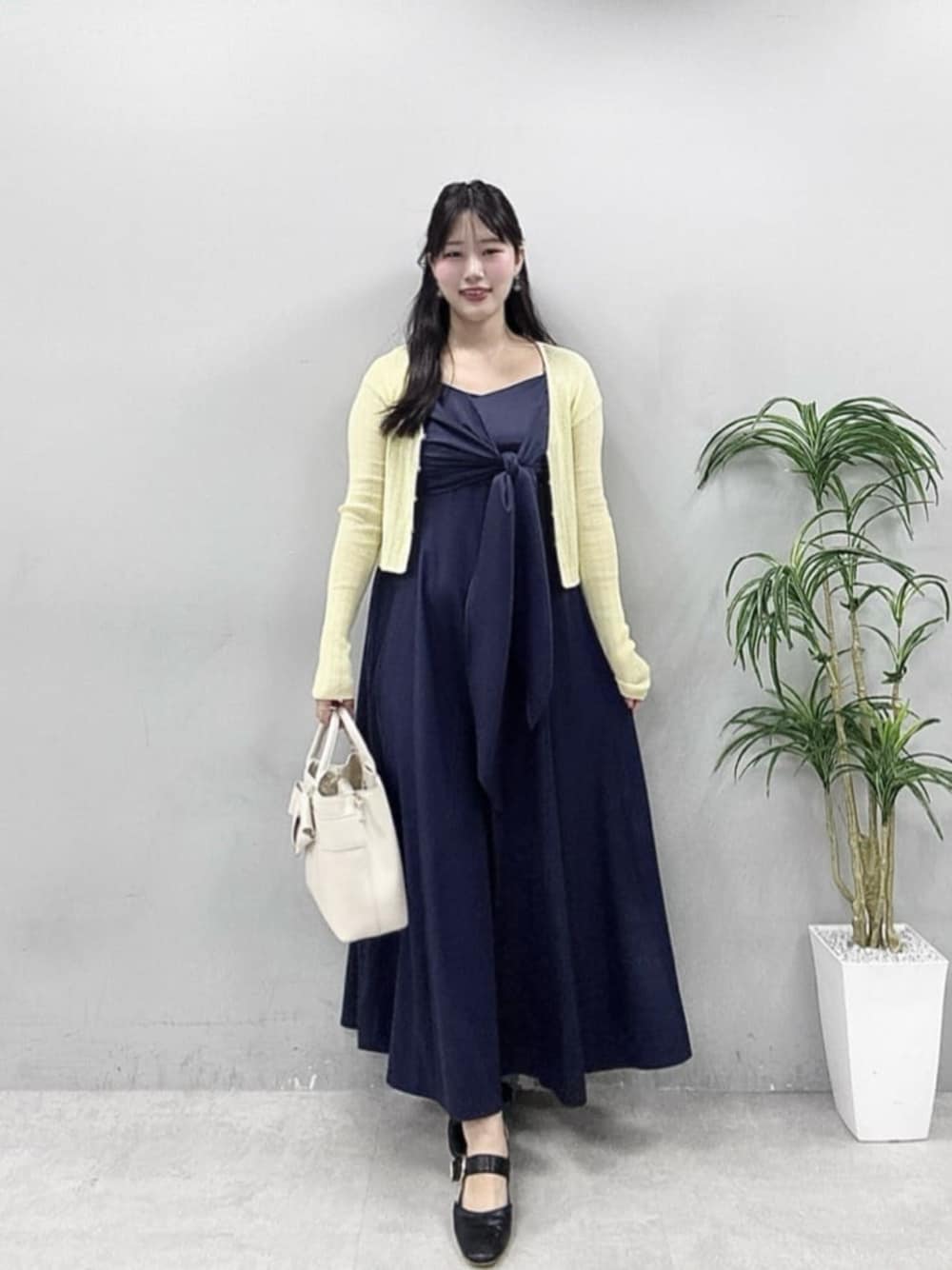 イエロー系のカーディガン/ボレロ、ブルー系のワンピースを着用したレディースの春コーディネートの1枚目の写真