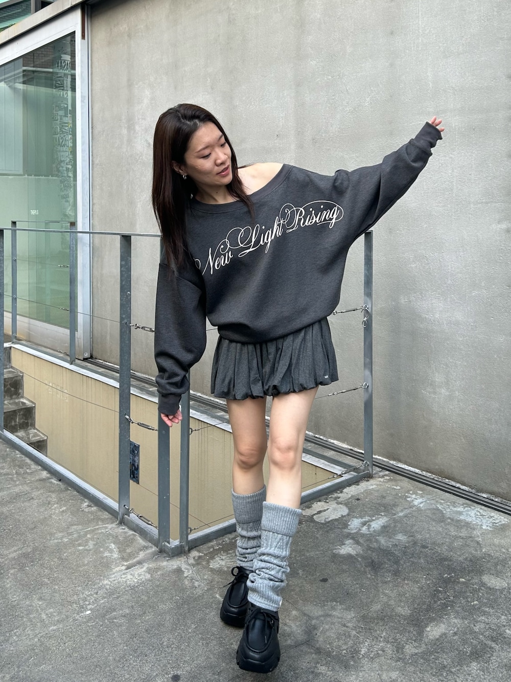 グレー系のスウェット、グレー系のスカート、ブラック系のローファーを着用したレディースの秋コーディネートの1枚目の写真