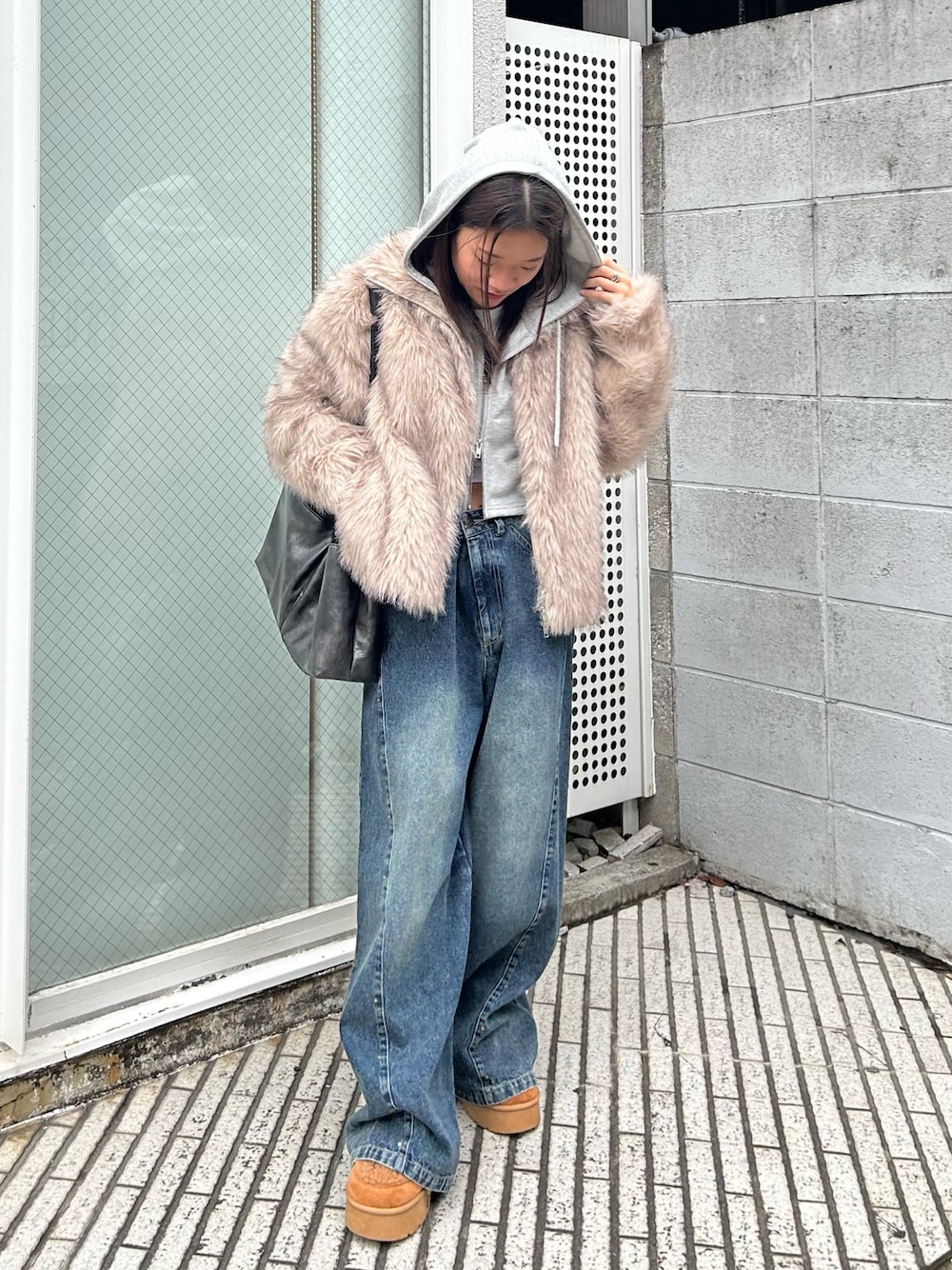 ブルー系のデニムパンツ、ブラック系のトートバッグ、イエロー系のブーツを着用したレディースの秋コーディネートの1枚目の写真