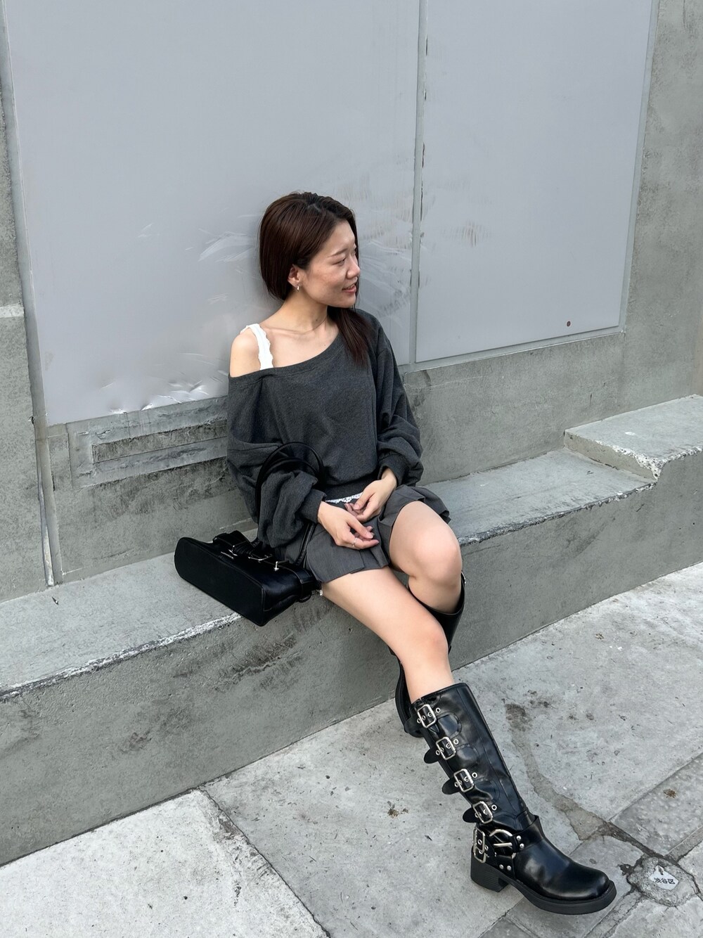 グレー系のスウェット、グレー系のスカート、ブラック系のブーツを着用したレディースの秋コーディネートの1枚目の写真