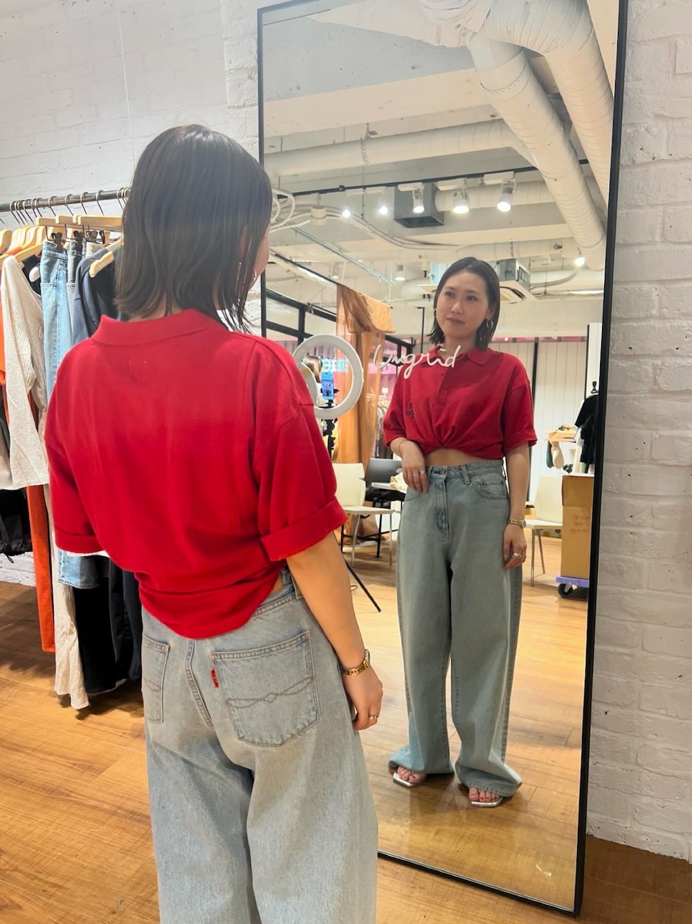 レッド系のポロシャツ、ブルー系のデニムパンツを着用したレディースの春コーディネートの1枚目の写真