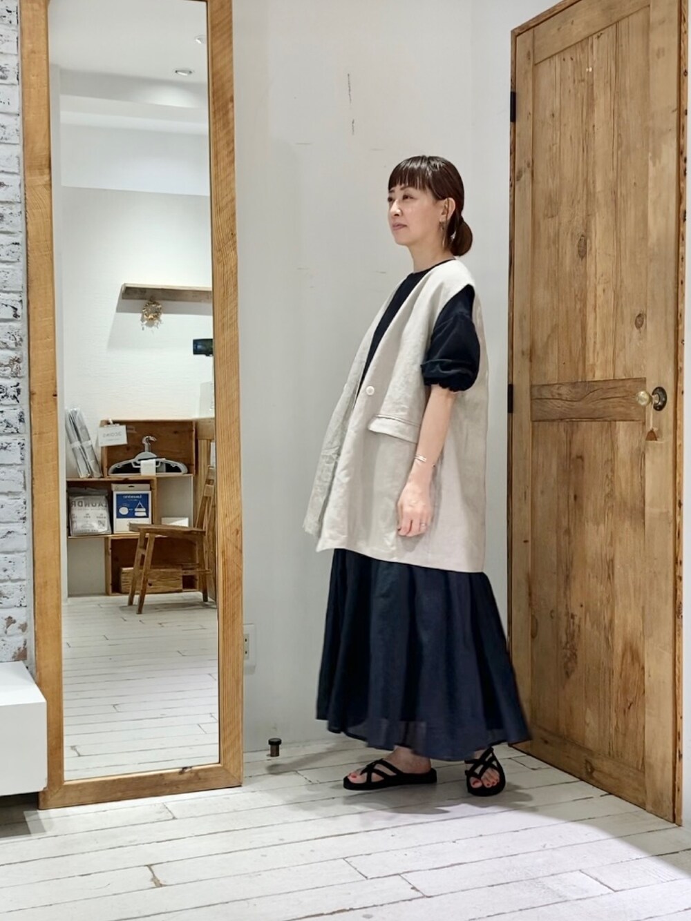 ベージュ系のベスト、ブラック系のワンピースを着用したレディースの夏コーディネートの2枚目の写真